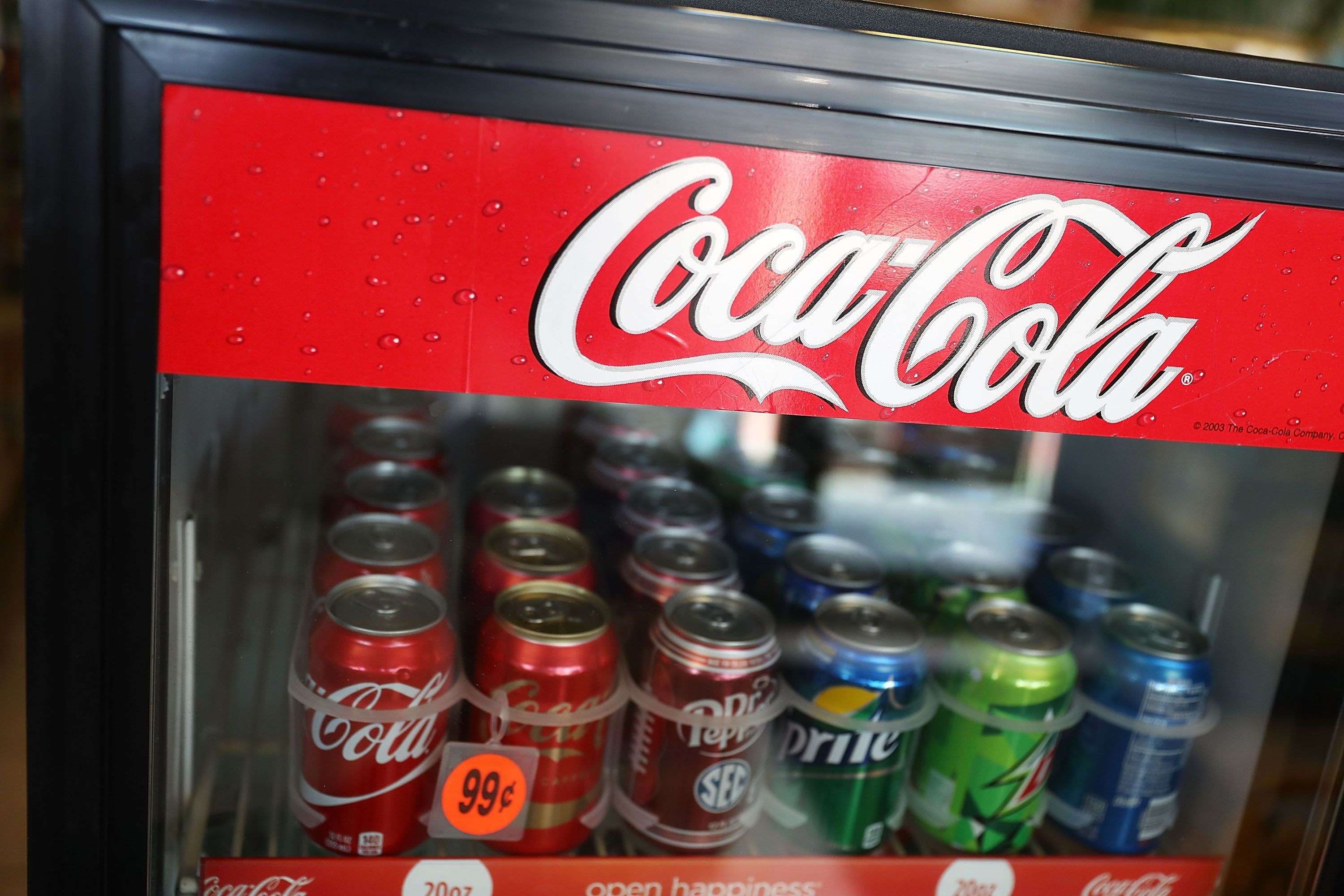 A Coca Cola sign is seen as Coke products are on display in a store as the company announces plans to cut 1200 corporate staff jobs. The announced changes come as the company battles a slide in soda sales which along with higher costs has lead to a 20 per cent drop in quarterly profit. Photo: AFP