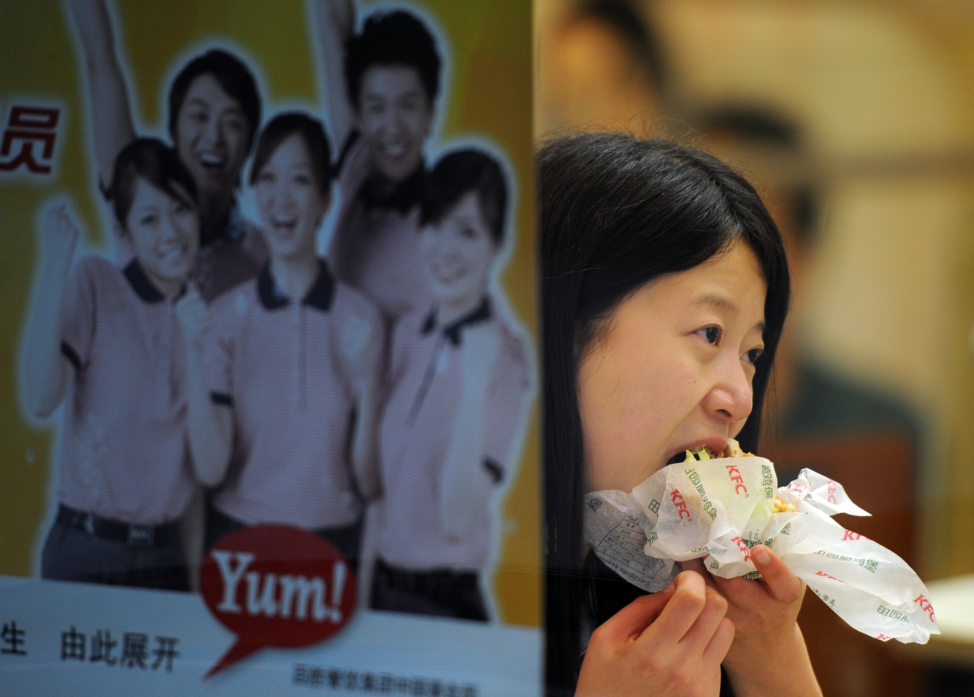 A woman eats a chicken burger in a branch of a KFC restaurant in Shanghai. Yum China Holdings, the operator of KFC and Pizza Hut restaurant chains across the country, is buying a controlling stake in food delivery service provider Daojia. Photo: AFP