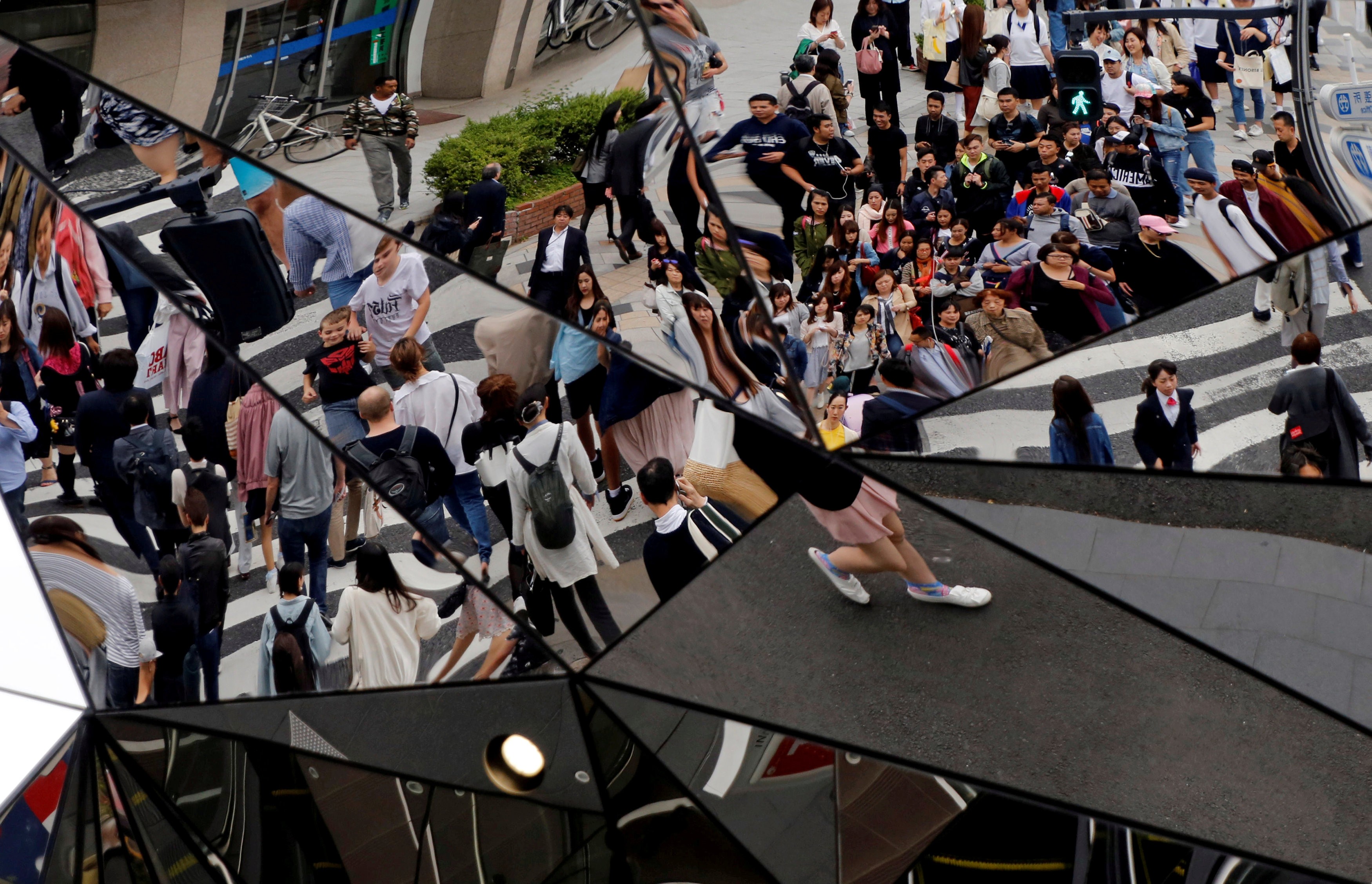 People are reflected in mirrors as they walk through a busy shopping district in Tokyo this month. Japanese Prime Minister Shinzo Abe’s plan to end deflation and increase competitiveness is in need of a boost. Photo: Reuters