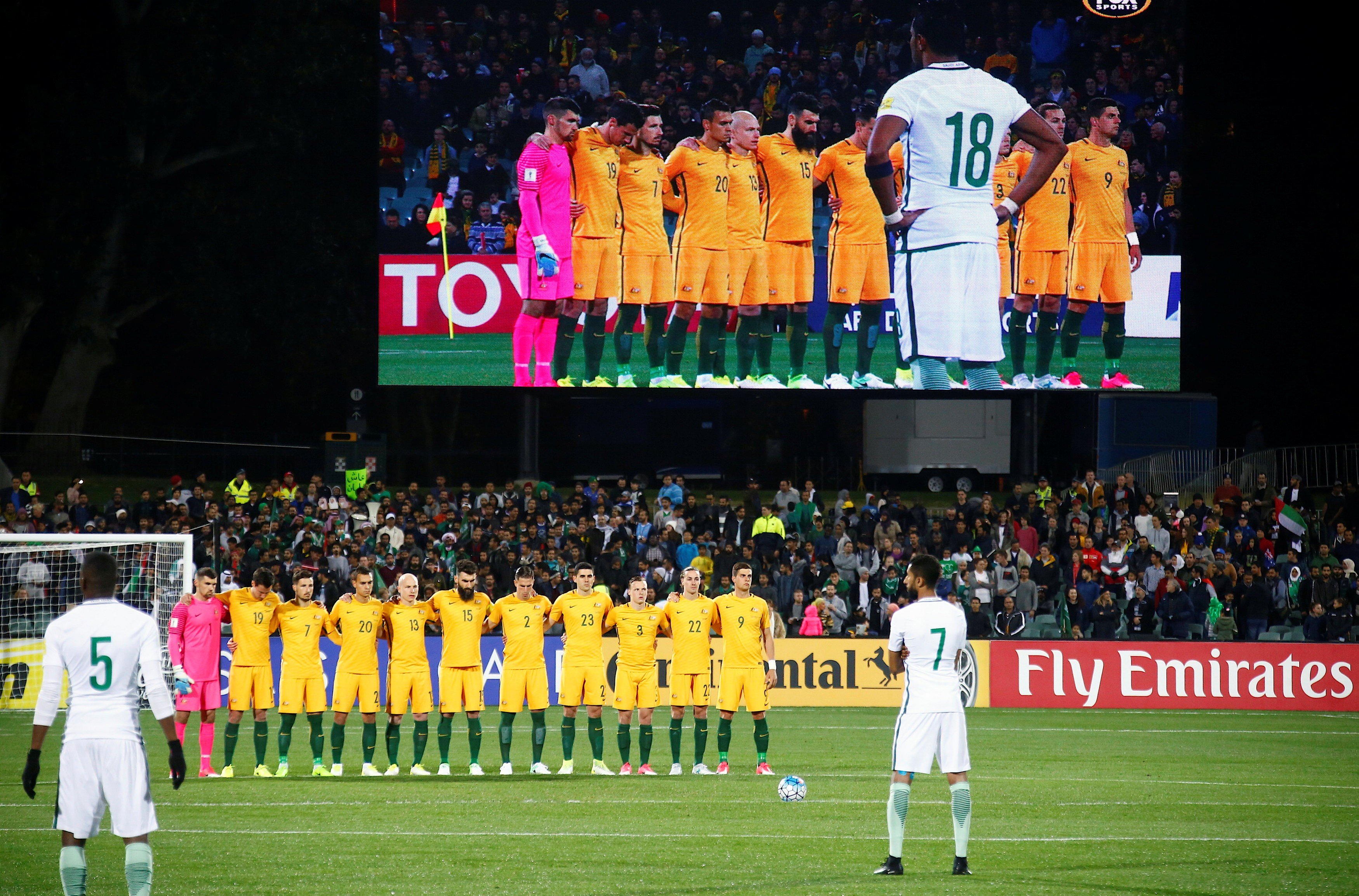 The Australian national team stand together as they observe a minute’s silence as the Saudi Arabia players mill around during the tribute. Photo: Reuters