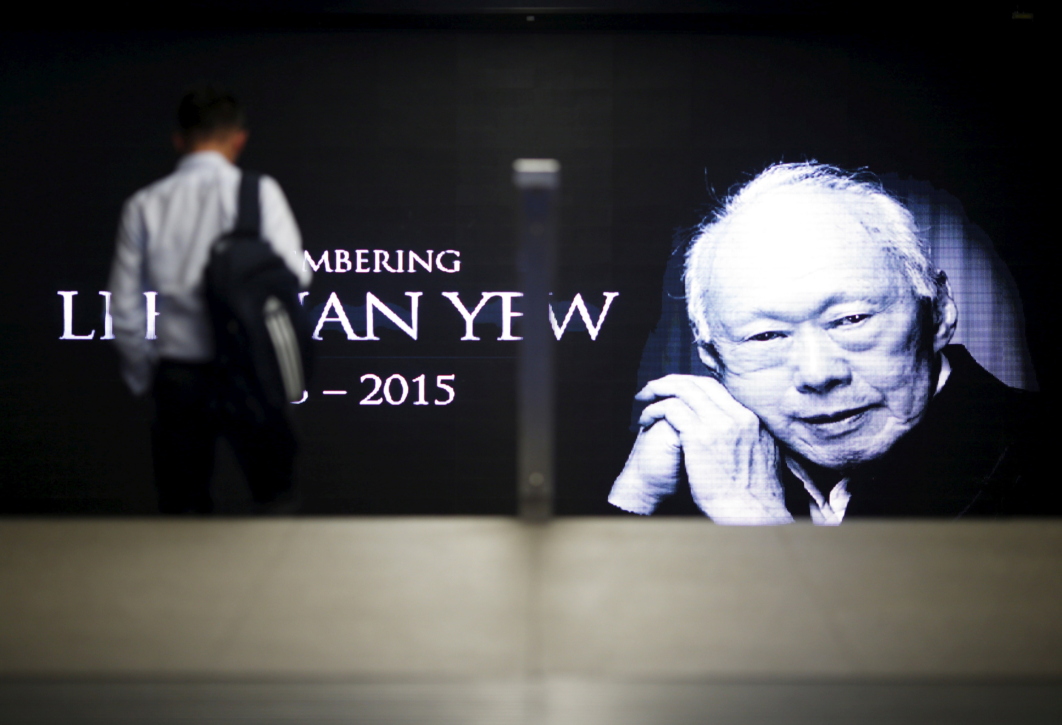 A commuter passes by a signboard bearing an image of the late Lee Kuan Yew at a train station in Singapore, in March 2015. Photo: Reuters