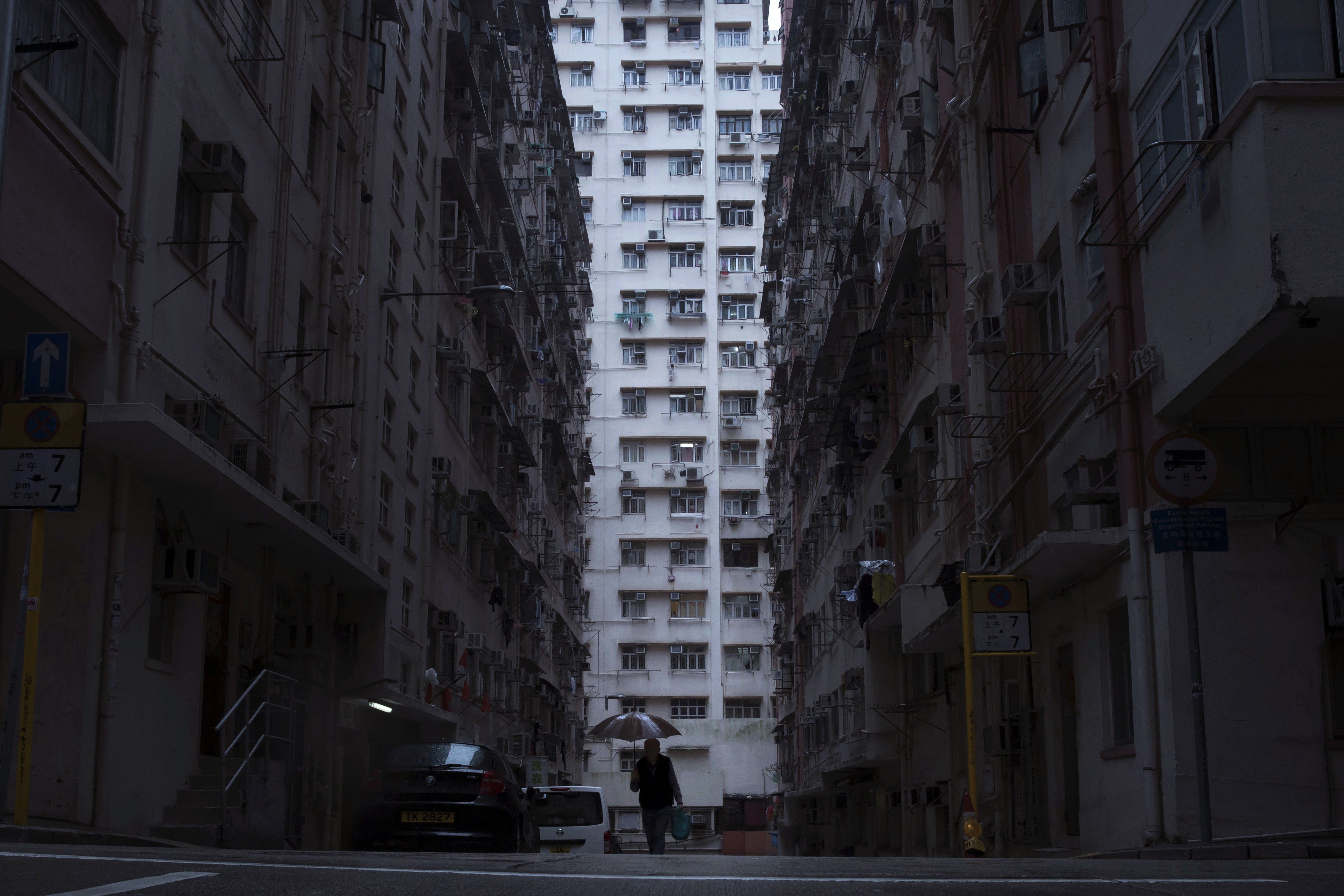 A man walks in front of a residential and commercial building, where so-called "coffin homes" are located in Hong Kong. In wealthy Hong Kong, there's a dark side to a housing boom, with hundreds of thousands of people forced to live in partitioned shoebox apartments, "coffin homes" and other "inadequate housing. Photo: AP Photo