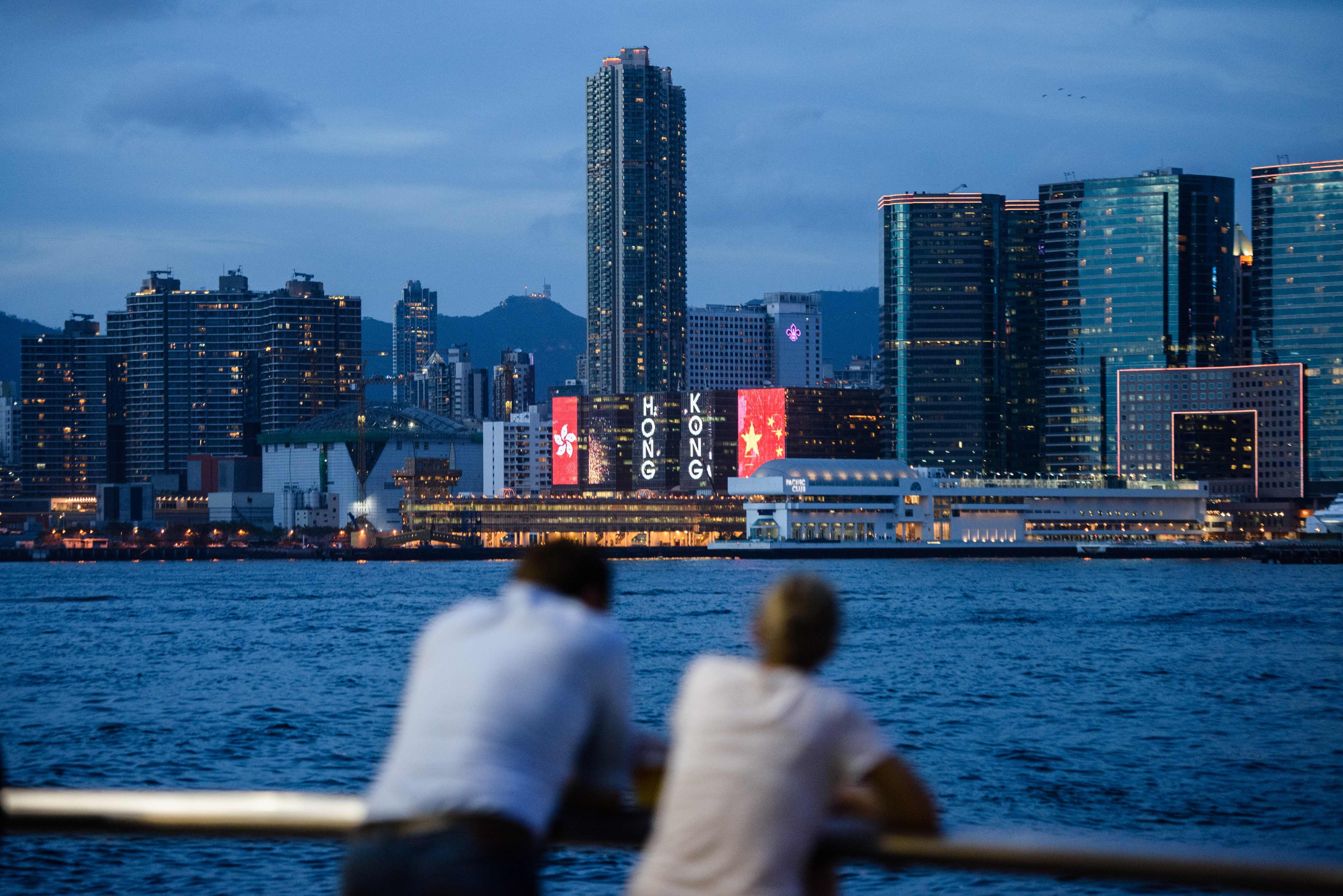 Two friends chat in front of a view of Victoria Harbour and a light display commemorating the 20th anniversary of the city's handover from British to Chinese rule in Hong Kong, ahead of the handover anniversary on July 1. Photo: AFP