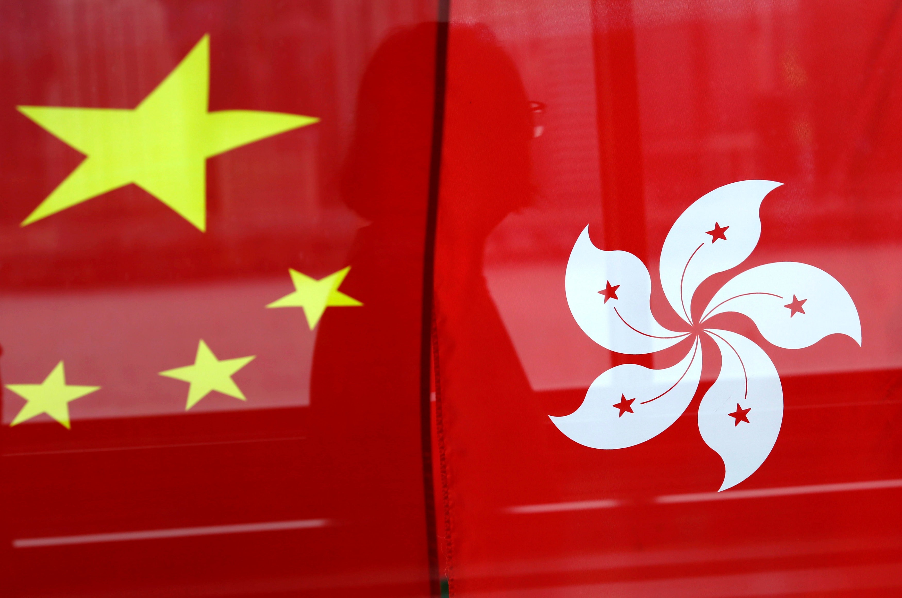 A woman is reflected in a window behind Chinese and Hong Kong flags after celebrations commemorating the 20th anniversary of Hong Kong's handover. That Hong Kong is a part of China is in the constitution, and that constitutional framework must become reality that is accepted by all. Photo: Reuters