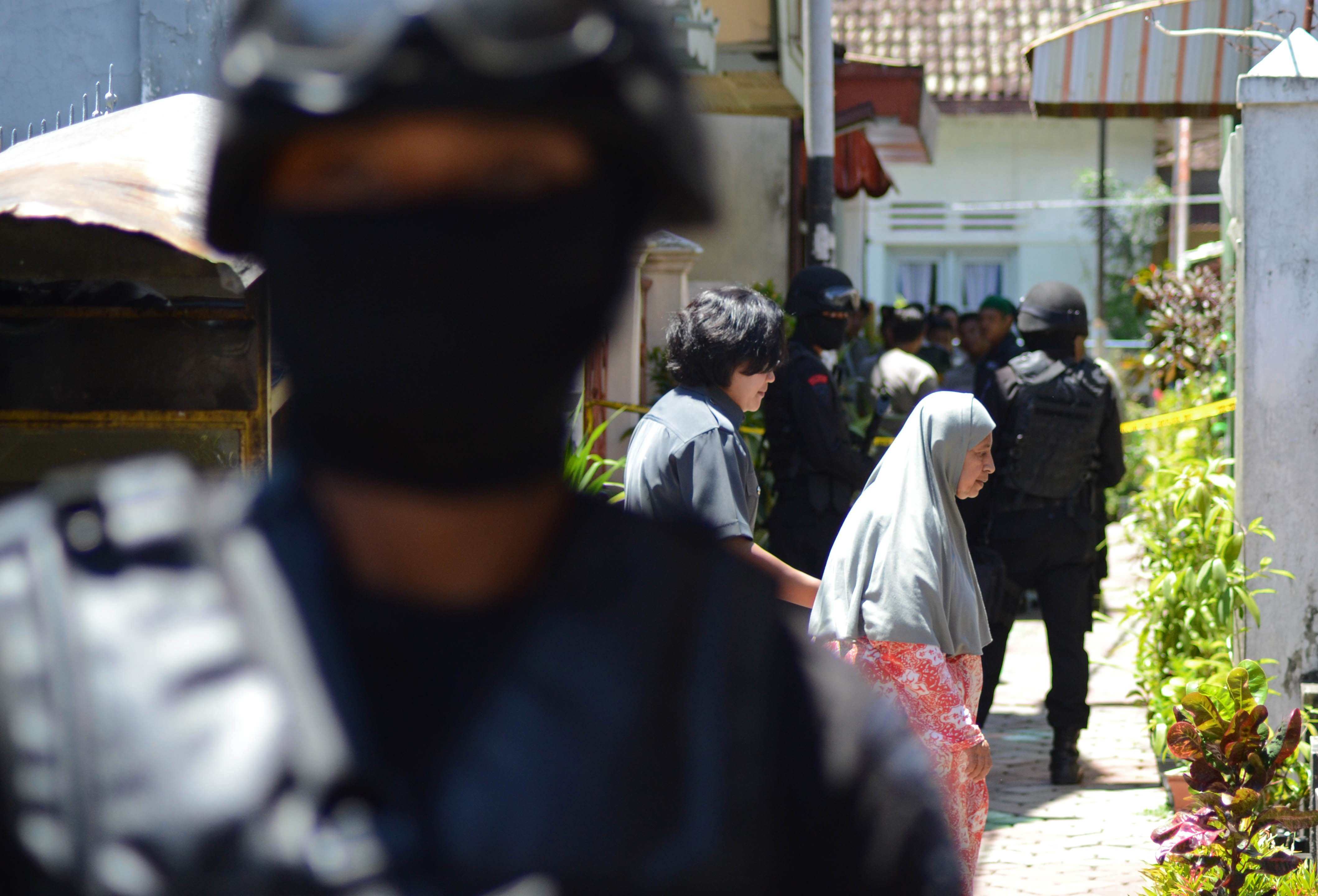 Civilian women walk as Densus 88 counterterrorism police commandos conducting operations on a house in Malang located in eastern Java island. Photo: AFP