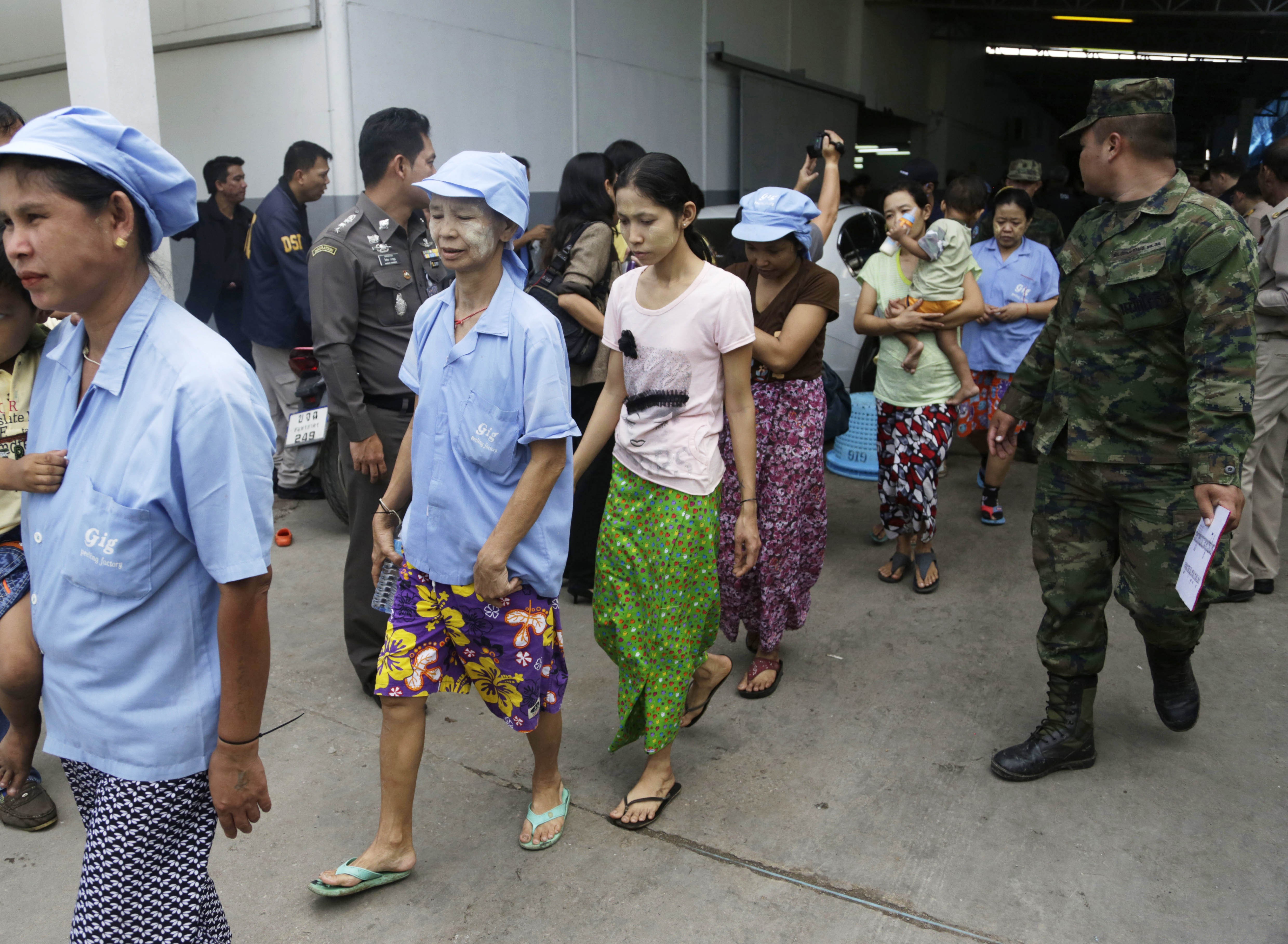 Myanmese workers are escorted by soldiers and police officers as they leave a shrimp shed after a raid conducted by Thailand's Department of Special Investigation in Samut Sakhon, Thailand. Photo: AP Photo