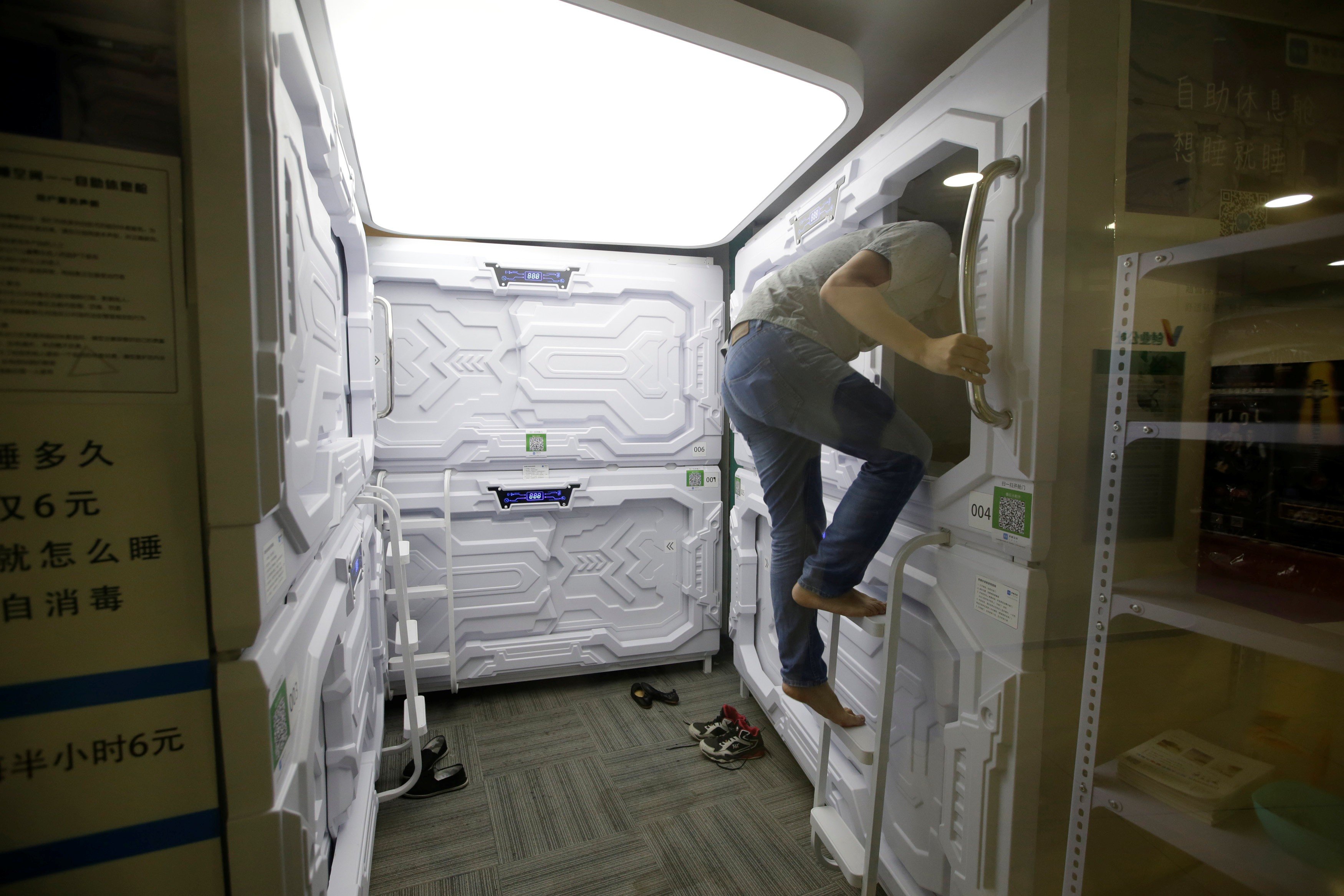 A man climbs up a ladder as he prepares to sleep in a capsule bed unit at Xiangshui Space during a lunch break in Beijing's Zhongguancun area. Photo: Reuters