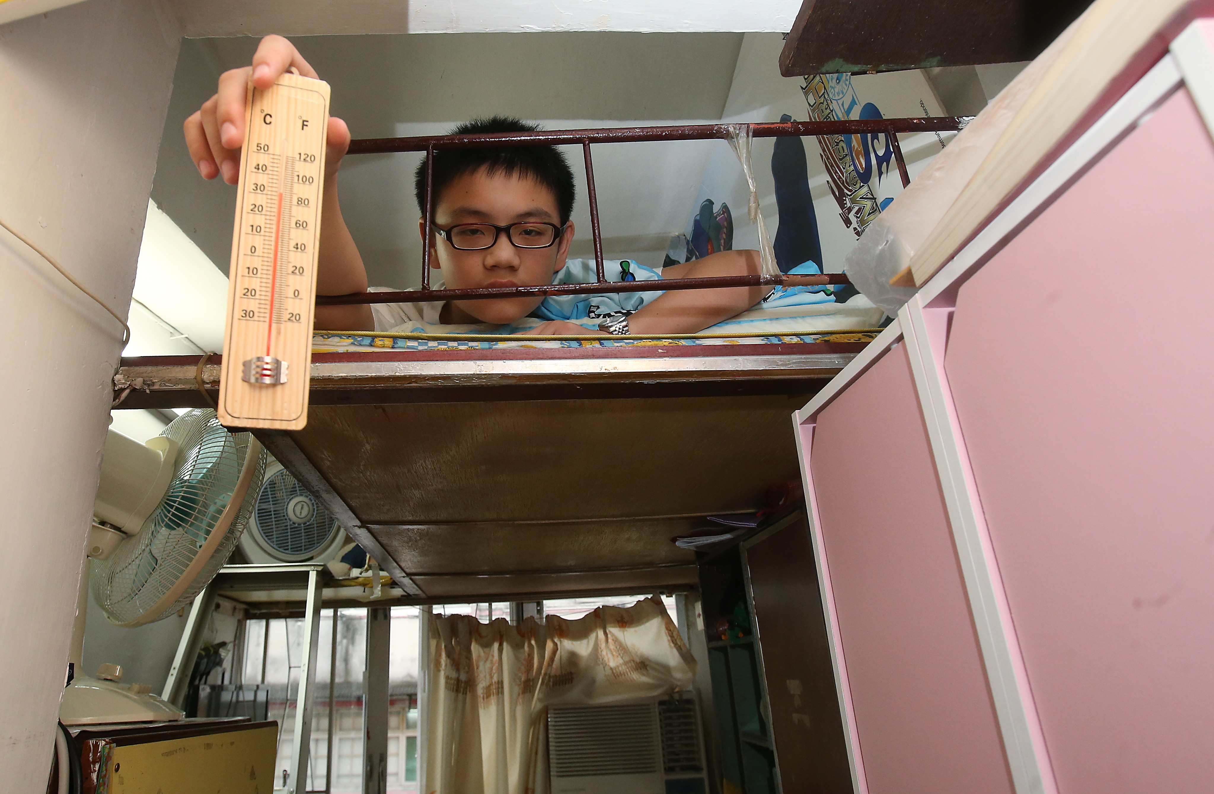Wong Chak-ming, 13, draws attention to the hot, suffocating conditions in his partitioned home in Sham Shui Po, on July 2. Photo: David Wong