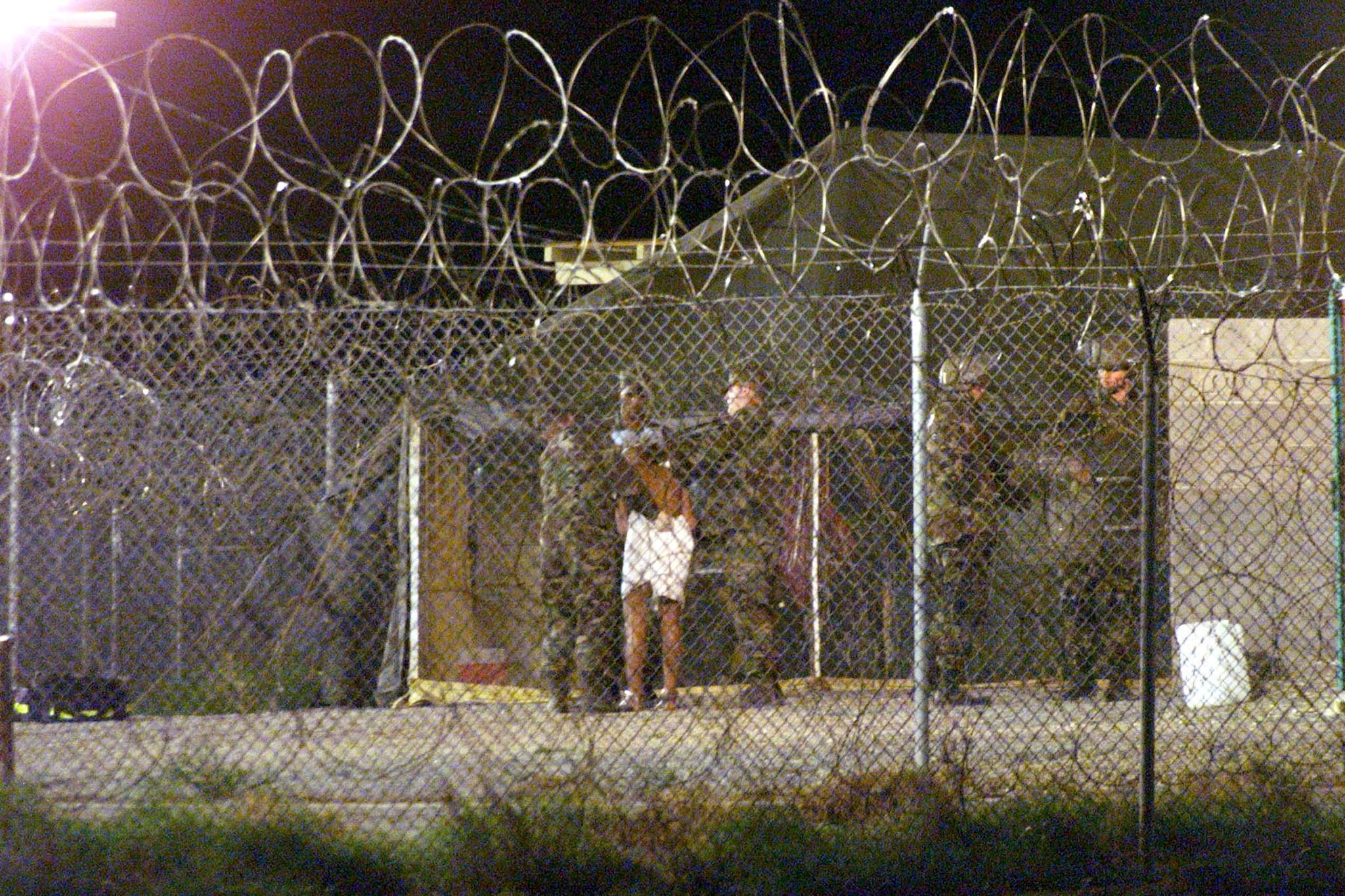 Marines at Camp X-Ray at the Naval Base at Guantanamo Bay, escort a newly arriving detainee into a processing tent after being showered in 2002. Photo: Reuters