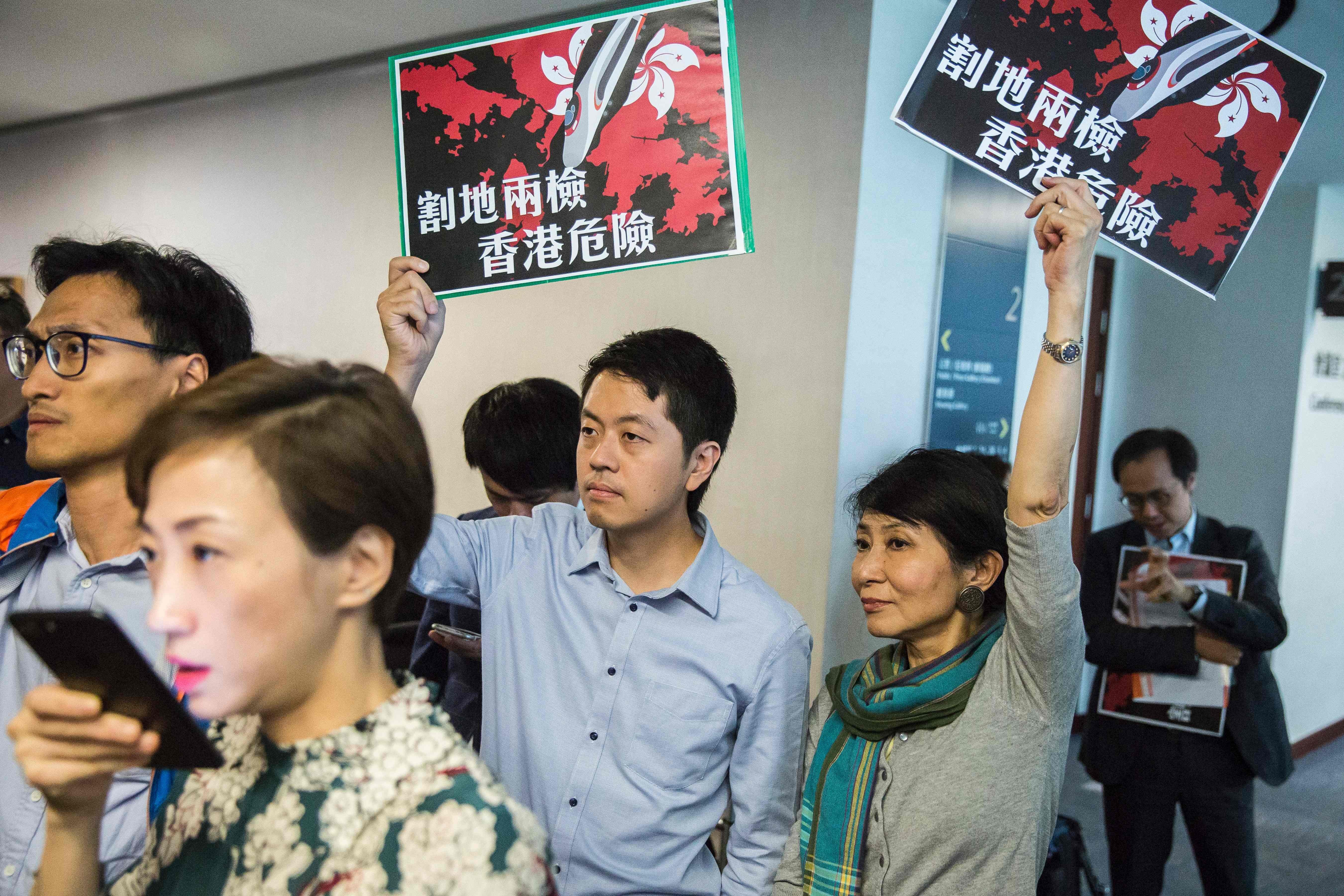 Pro-democracy lawmakers Ted Hui of the Democratic Party and Claudia Mo of the Civic Party hold signs that read “ceding land with co-location puts Hong Kong in danger” as Secretary for Justice Rimsky Yuen (not in picture) speaks at a press conference in Hong Kong, on August 3. Photo: AFP