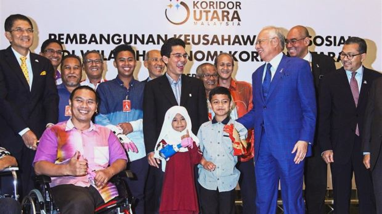 Najib sharing a light moment with Pak Su as Fathul (centre), Redza (second from right) and other prosthetic limb recipients look on in Putrajaya. Photo: The Star