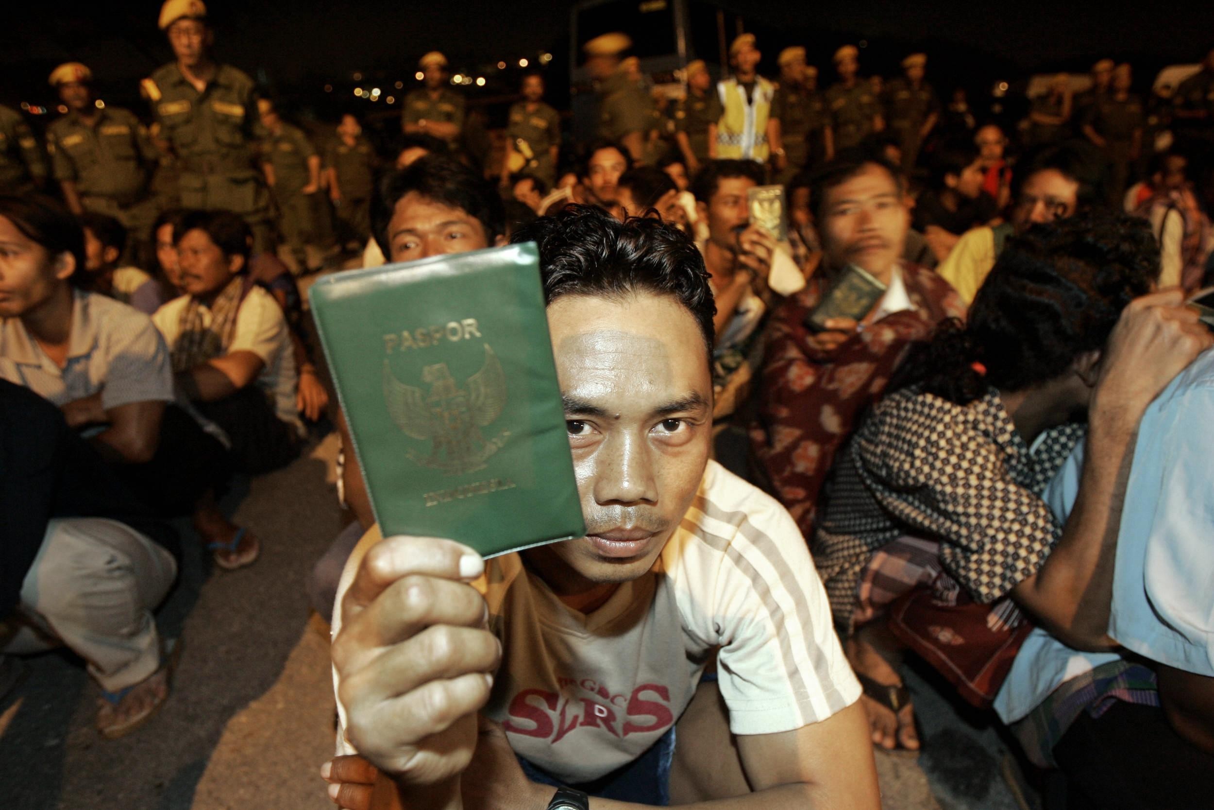 An Indonesian migrant worker in Kuala Lumpur shows his passport during a late-night immigration raid. Photo: AFP