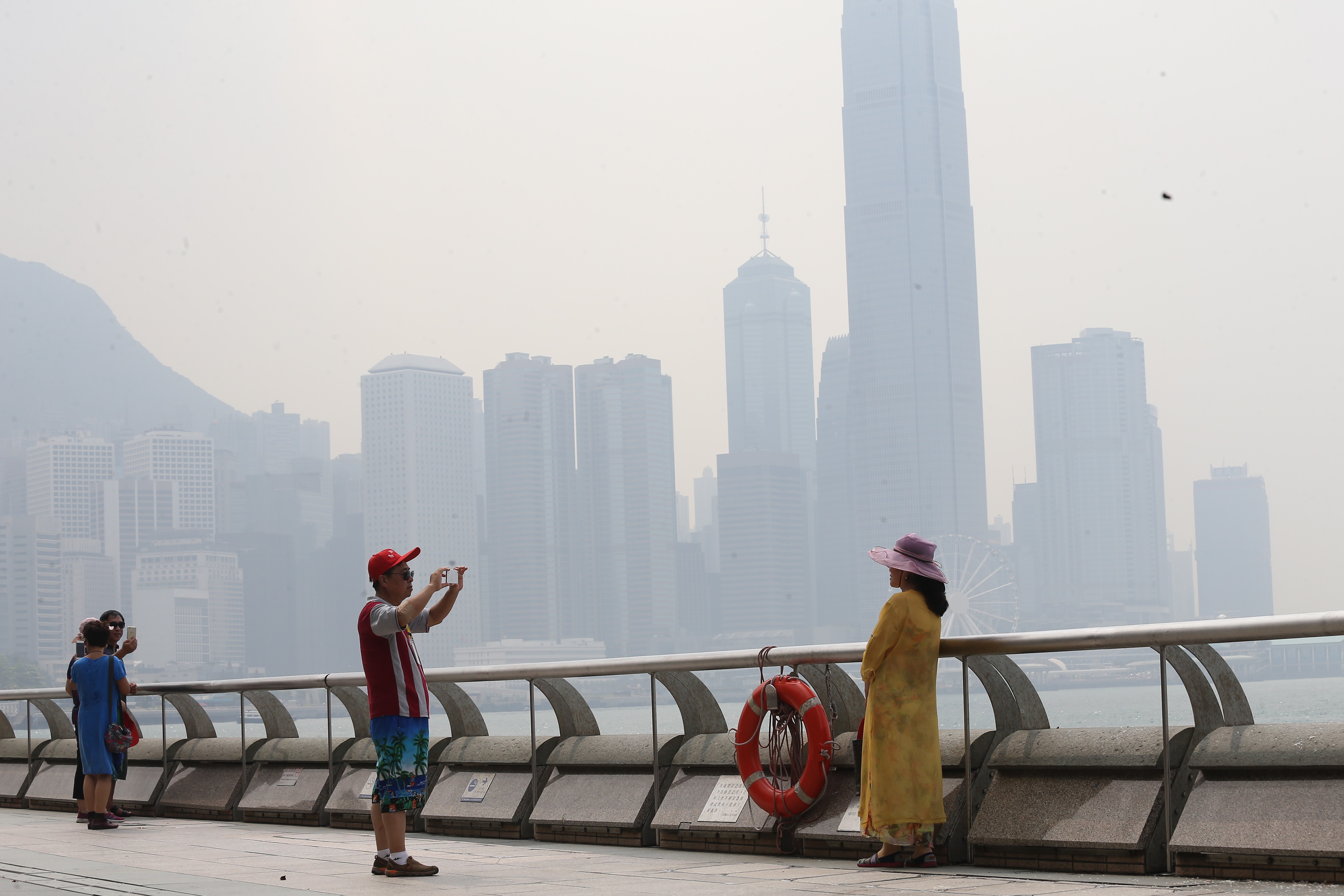 Tourists take pictures in Tsim Sha Tsui amid hazy conditions. Photo: Dickson Lee