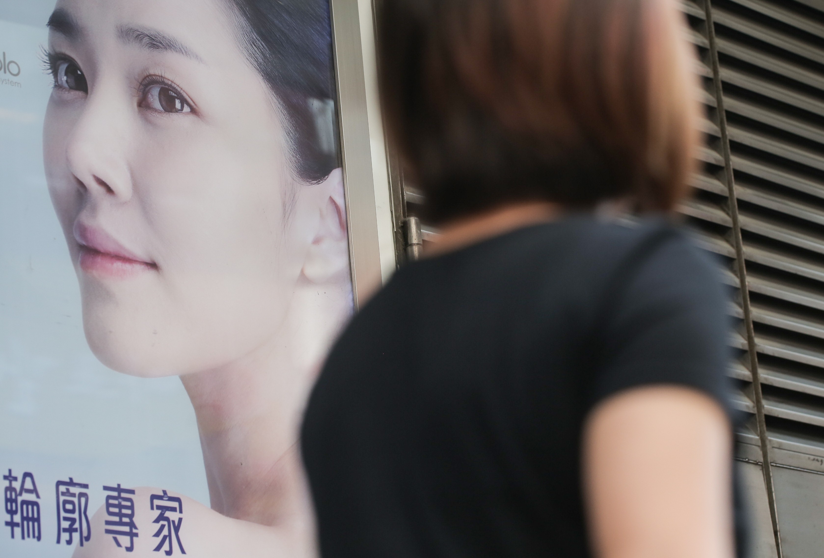 Women walk past an advertisement of beauty centre on the street in Causeway Bay. Consumer Council has urged the government to regulate beauty treatment requiring medical procedures. Photo: Paul Yeung