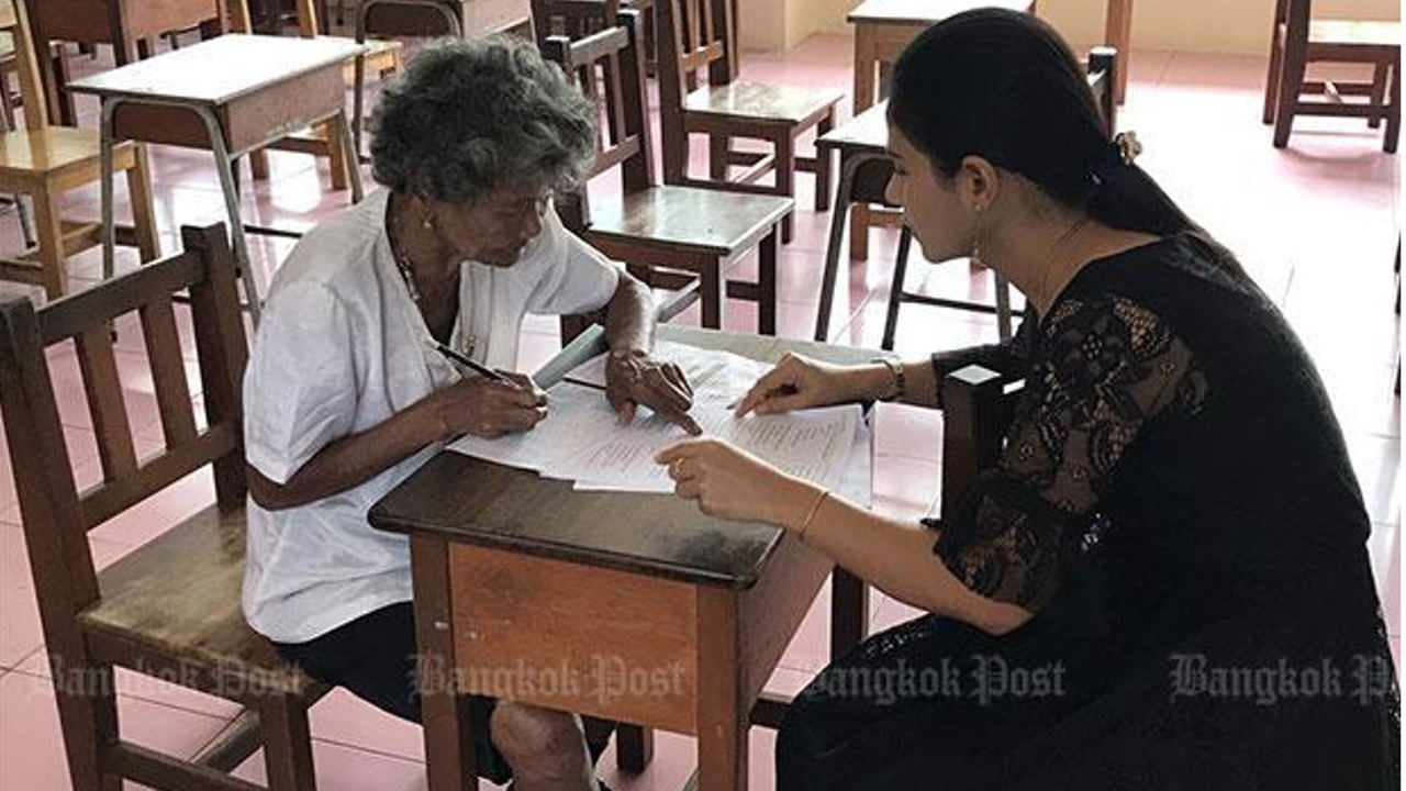 Prapasri Paowal, head of the the Non-Formal and Informal Education Office in tambon Kuan Pring of Trang, gives exam instructions to her oldest student, Grandma Khlong Faikhao. Photo: Methee Muangkaew/Bangkok Post