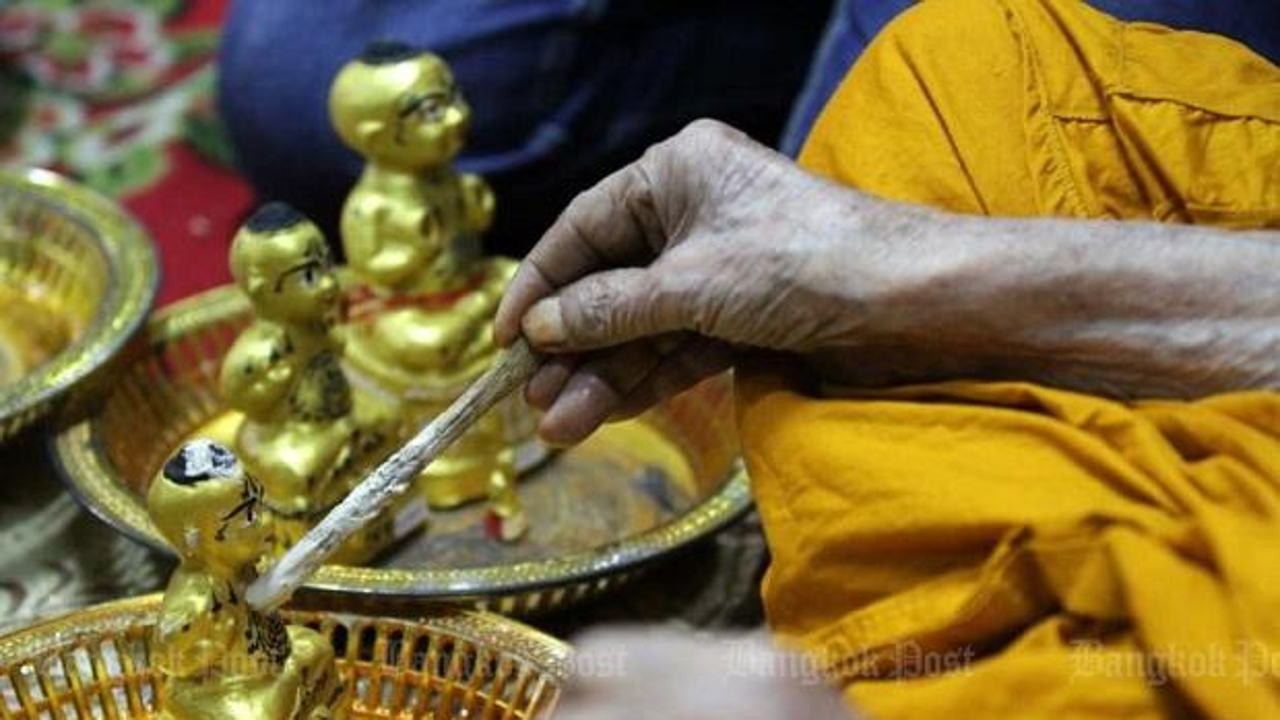 A monk consecrates a kumarn thong, a popular talisman many people believe has magical protective properties and can bring good fortune. Photo: Bangkok Post