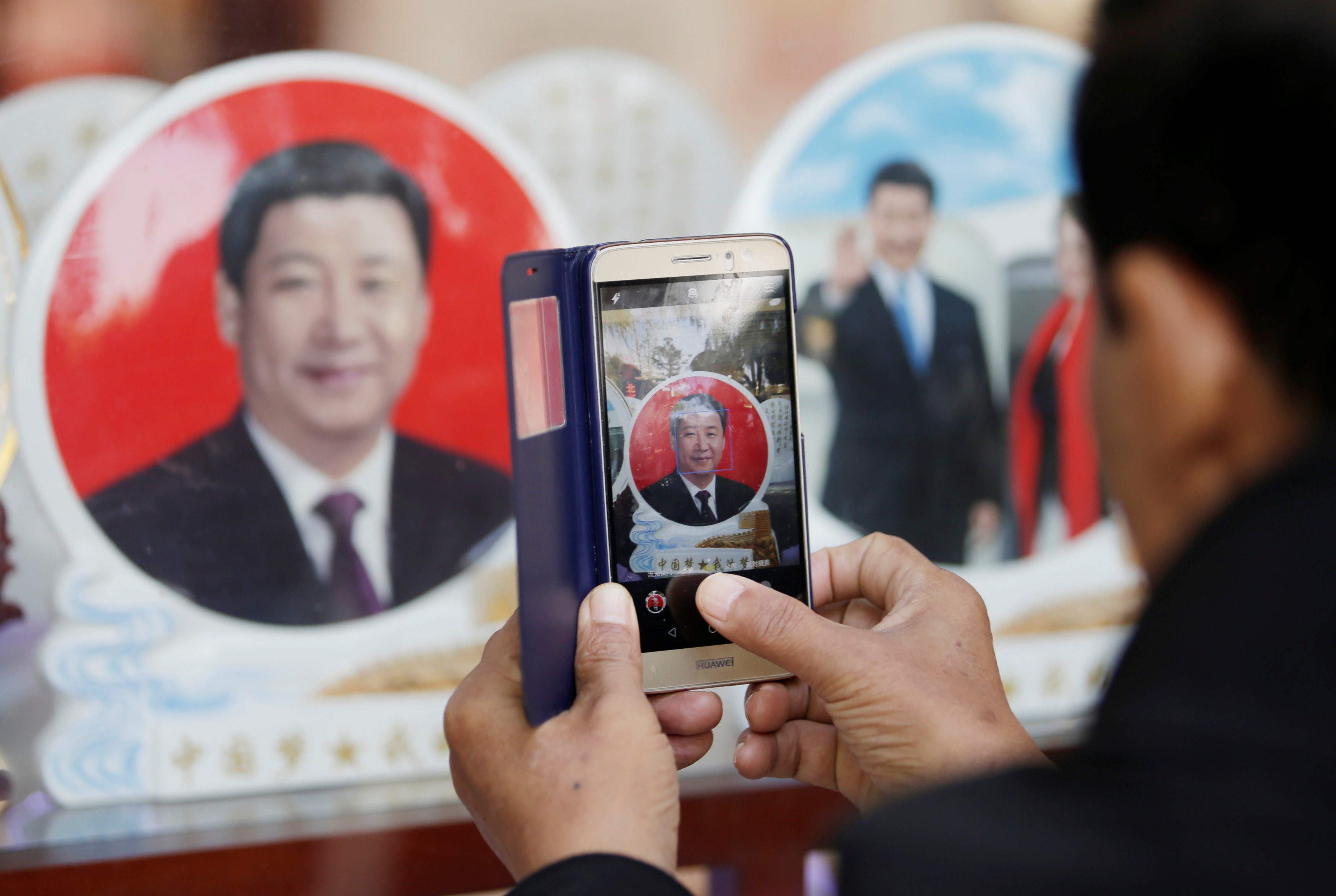 A tourist takes a picture of the souvenir plate with image of Chinese President Xi Jinping outside a shop next to Tiananmen Square. Photo: Reuters