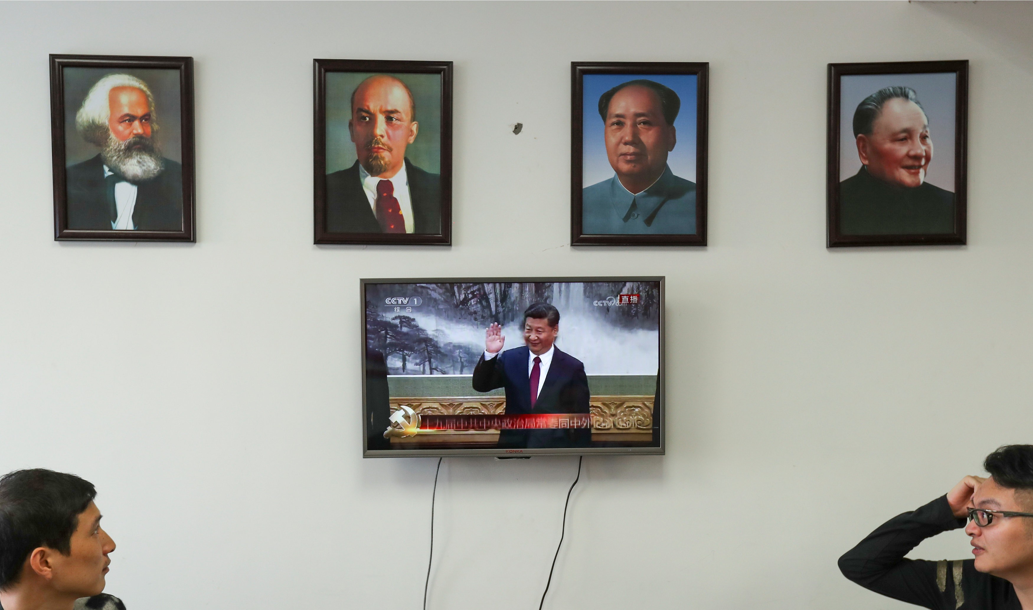 Framed portraits of German philosopher Karl Marx, Soviet state founder Vladimir Lenin and China's late leaders Mao Zedong and Deng Xiaoping (L-R) hang above a screen showing a news broadcast of China's President Xi Jinping attending a meeting in Beijing, as party members gather to watch the broadcast in Wenzhou, Zhejiang province, China October 25, 2017. Photo: Reuters