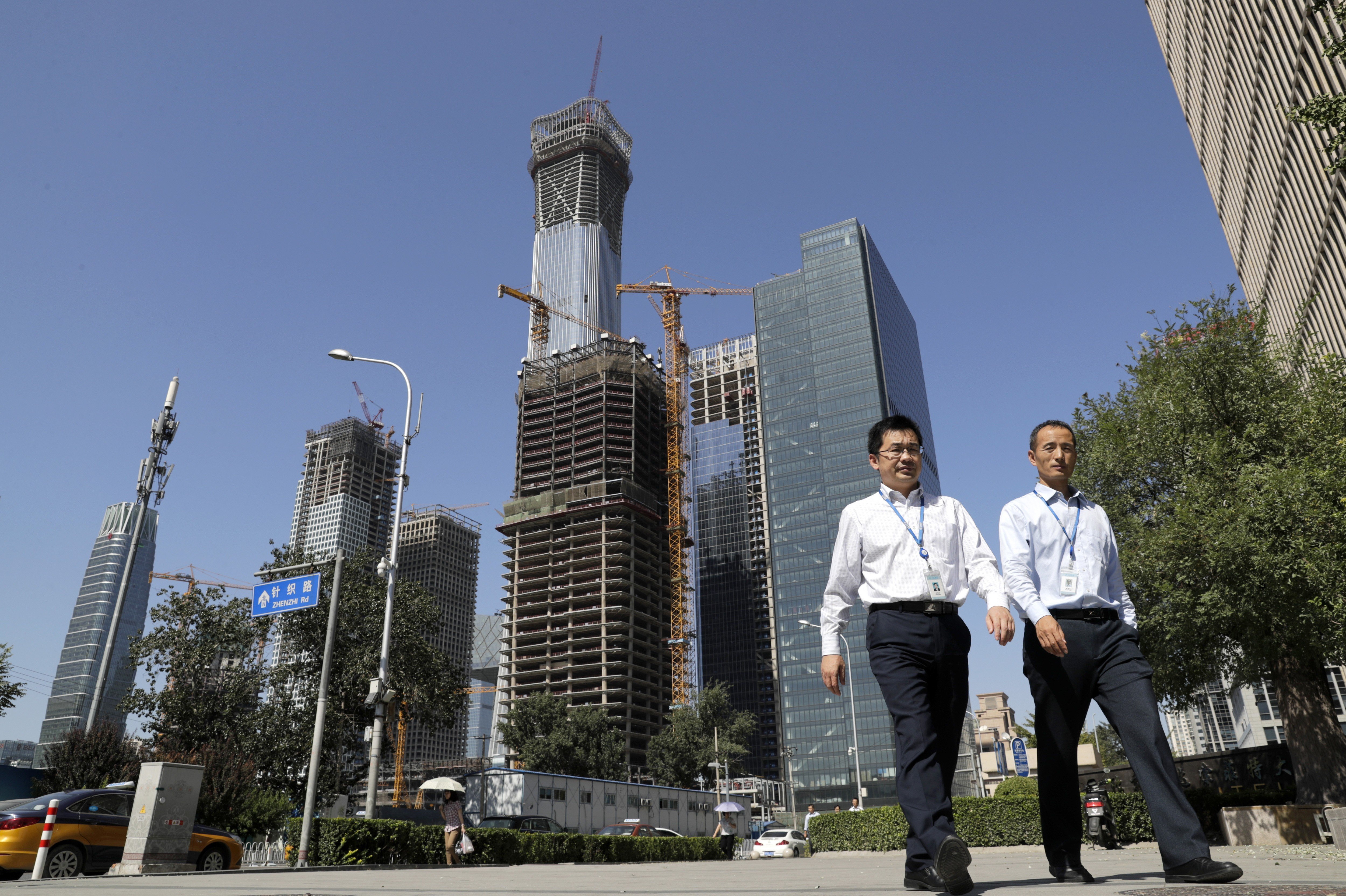 Chinese people walk by a construction site at the Central Business District in Beijing. By downplaying hard economic targets, future growth will slow down but be more balanced and sustainable. Photo: AP