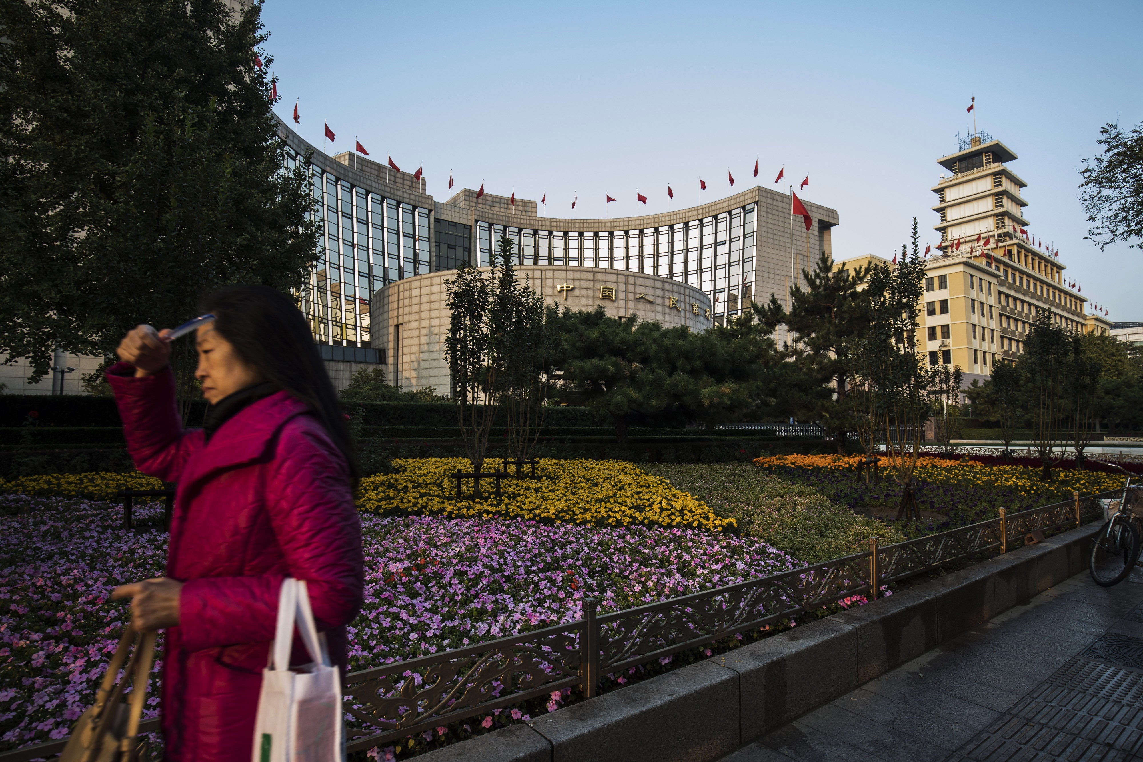 A pedestrian walks past the People's Bank of China headquarters in Beijing, China, on Monday, October 23, 2017. China's central bank is said to have gauged demand for 63-day reverse repurchase agreements for the first time ever. Photo: Bloomberg