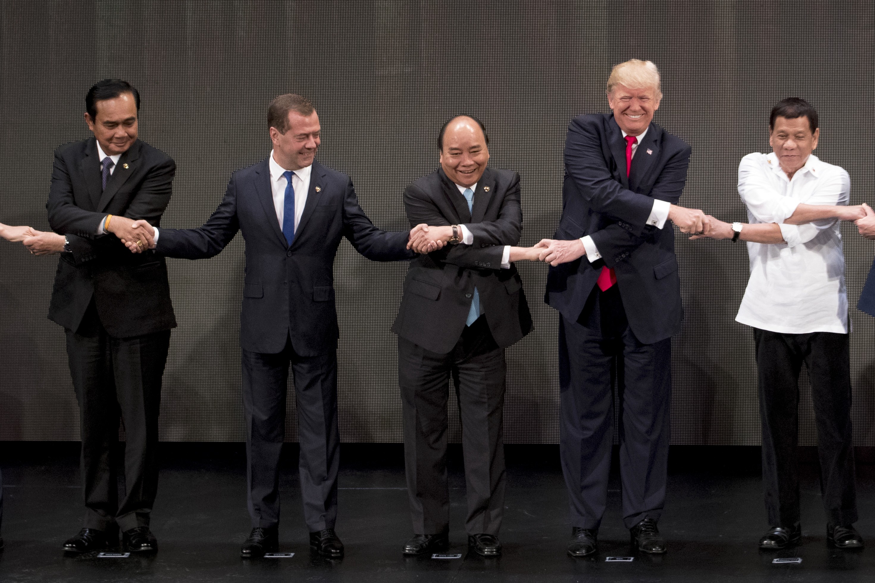 Vietnamese Prime Minister Nguyen Xhan Phuc (centre) joins hands with (from left) Thai Prime Minster Prayuth Chan-ocha, Russian Prime Minister Dmitry Medvedev, US President Donald Trump, and Philippine President Rodrigo Duterte in the “Asean-way handshake” on November 13 in Manila, at the opening ceremony for the Asean Summit. Photo: AP