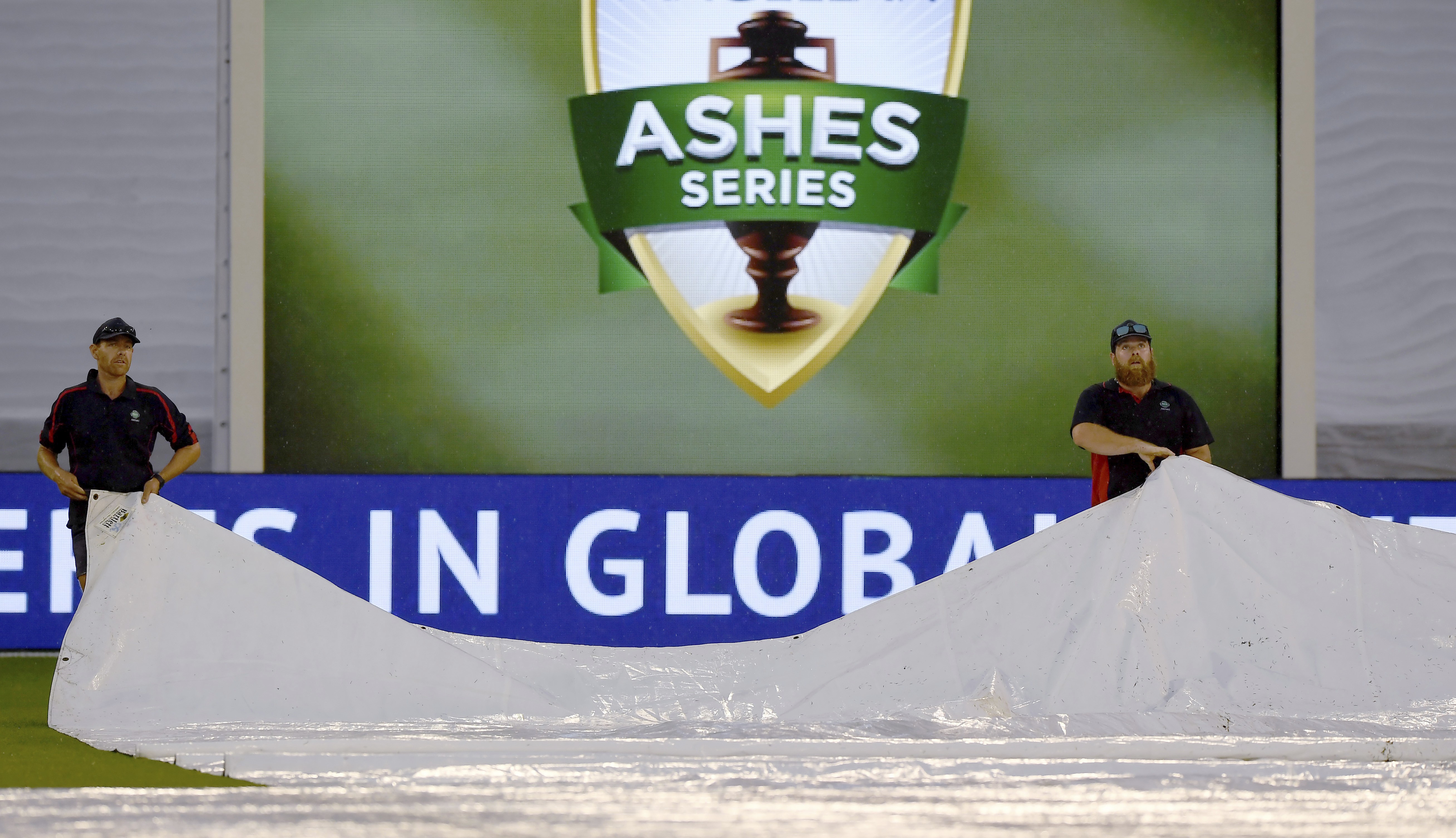 Grounds staff work on the field as rain delays play between England and Australia during the fourth day of their Ashes test in Melbourne. Photo: AP