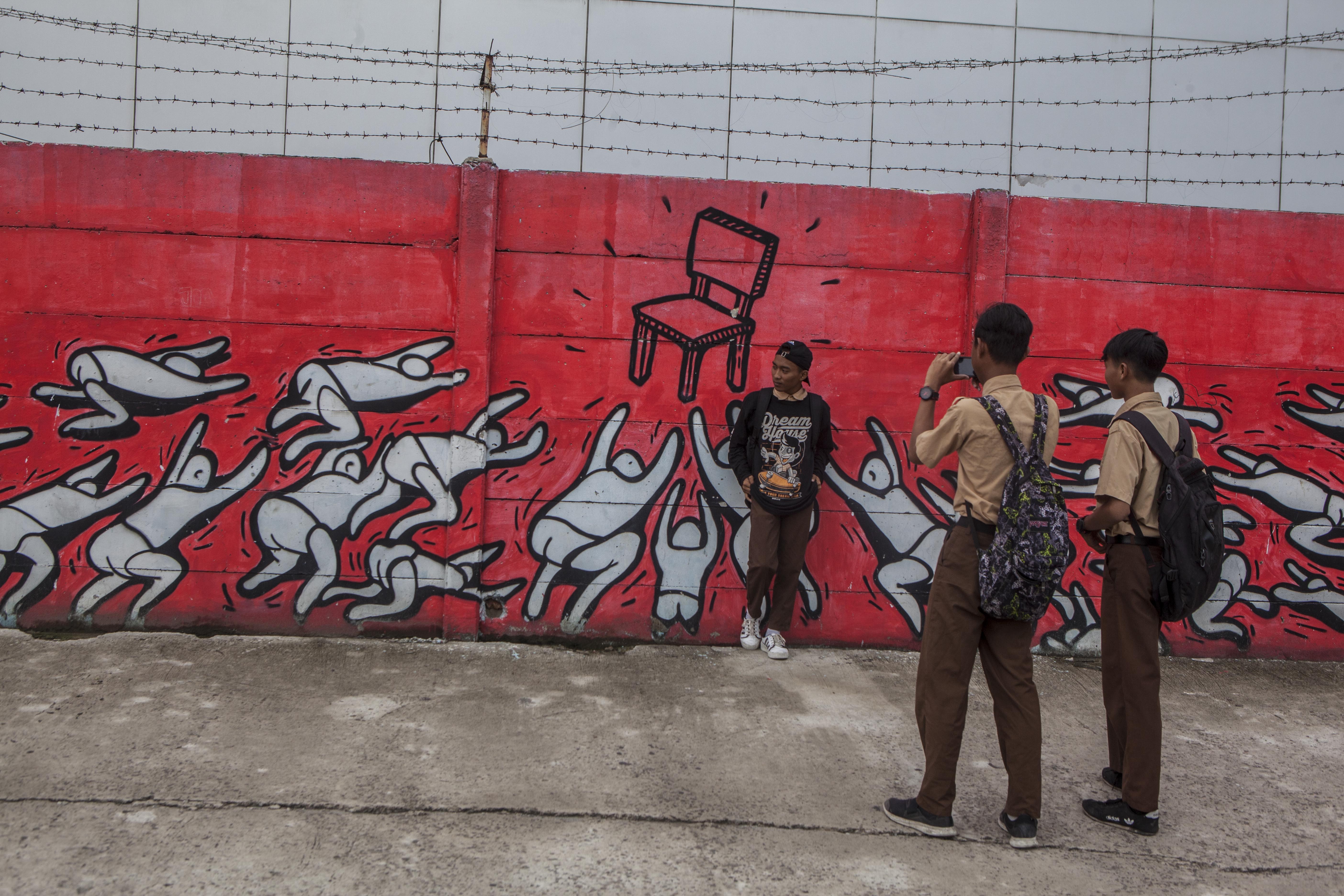 Students take photos in front of a mural by Popo in Jakarta, Indonesia. Photo: Agoes Rudianto