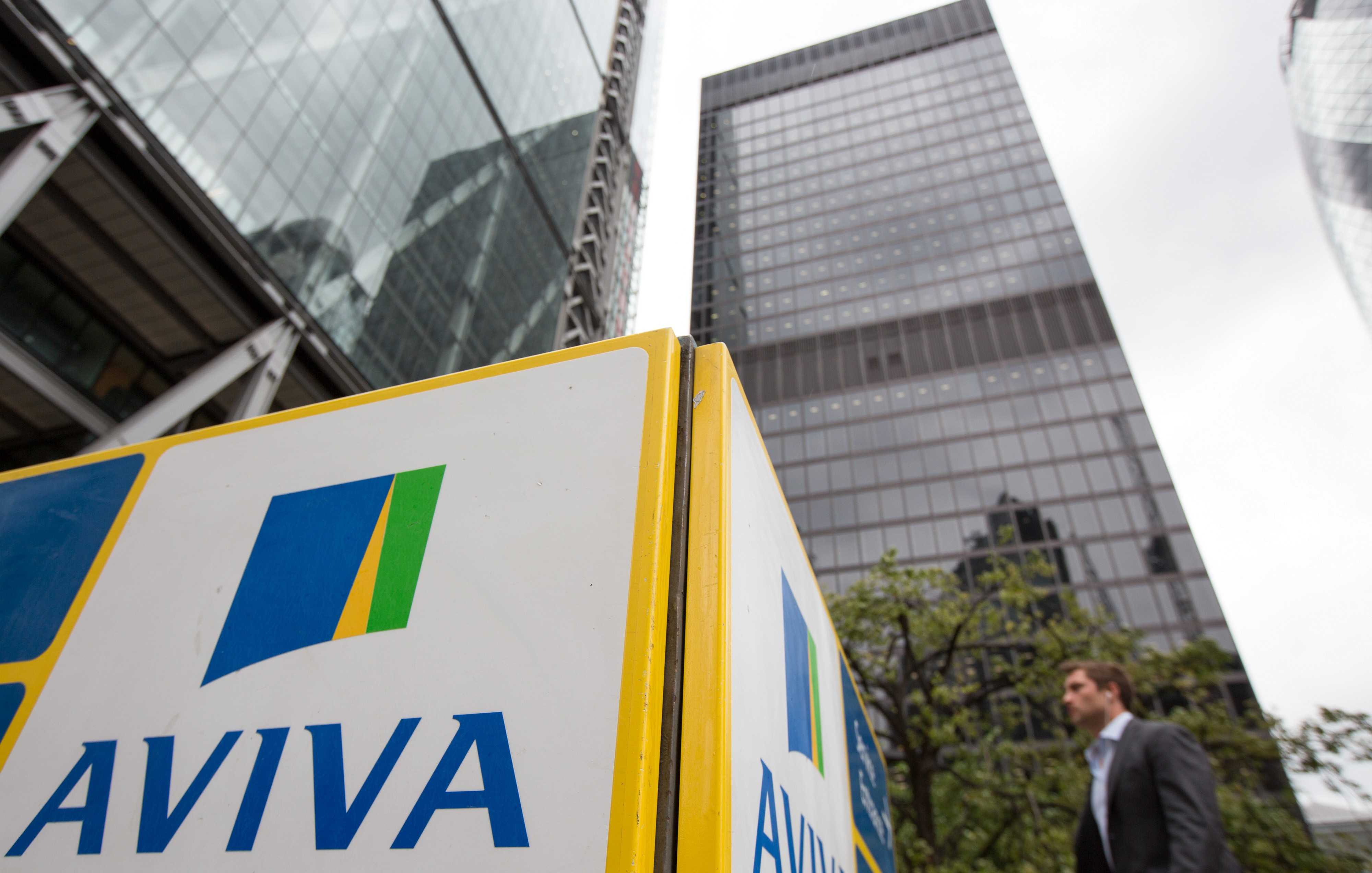 A pedestrian walks near to an Aviva Plc logo on a sign outside the insurance company's headquarters in London, U.K., on Monday, Aug. 1, 2016. Aviva will release their half-year results on Aug 4. Photographer: Jason Alden/Bloomberg
