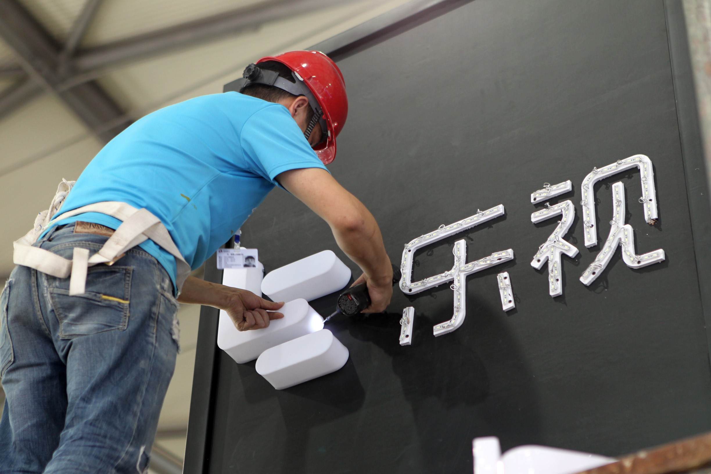 A worker installs the logo of LeEco, formerly known as Leshi or LeTV, in preparation for the 2016 International Consumer Electronics Show Asia. Photo: Imaginechina