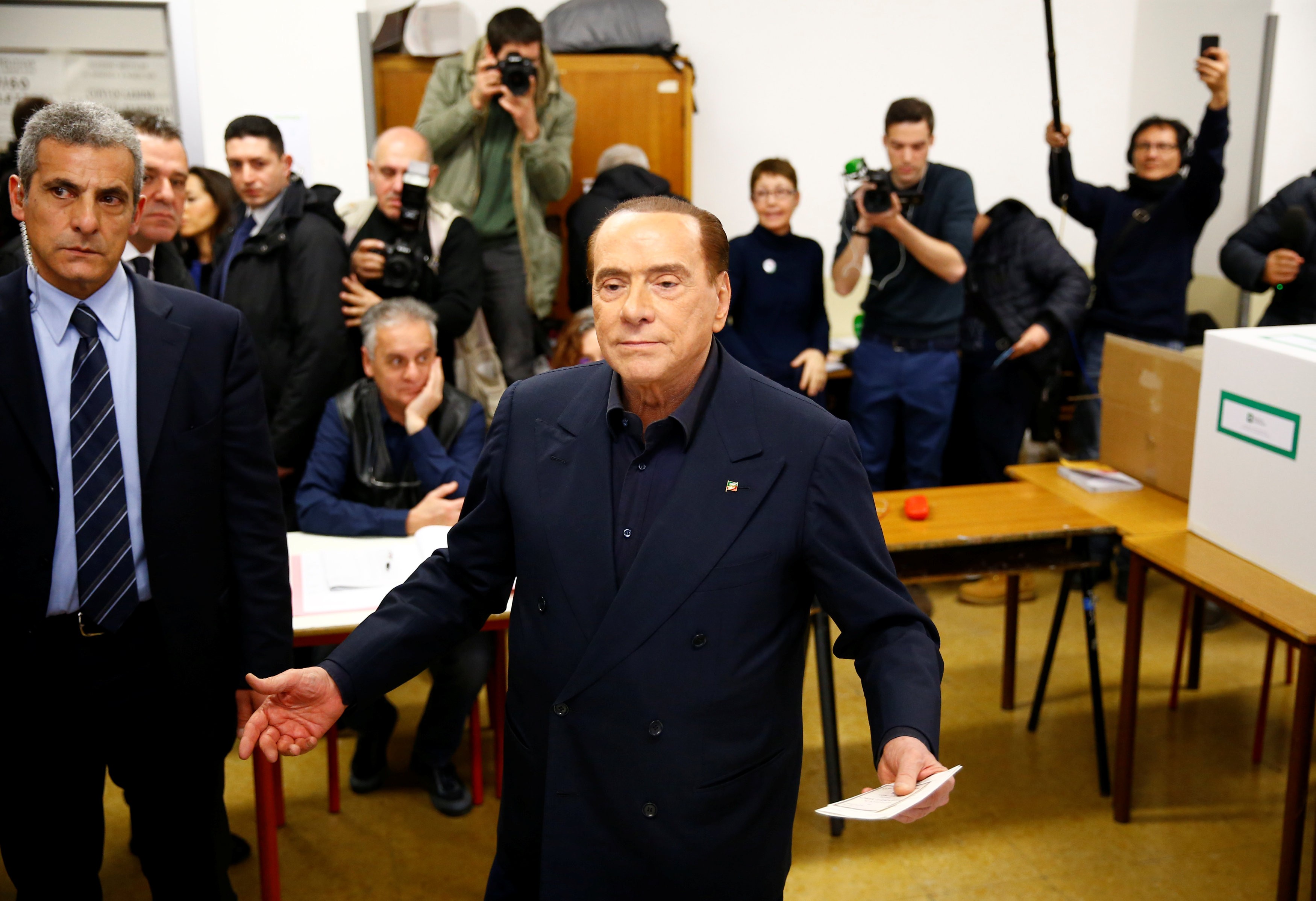 Former Italian premier Silvio Berlusconi listens to reporters at a polling station in Milan. Photo: Reuters