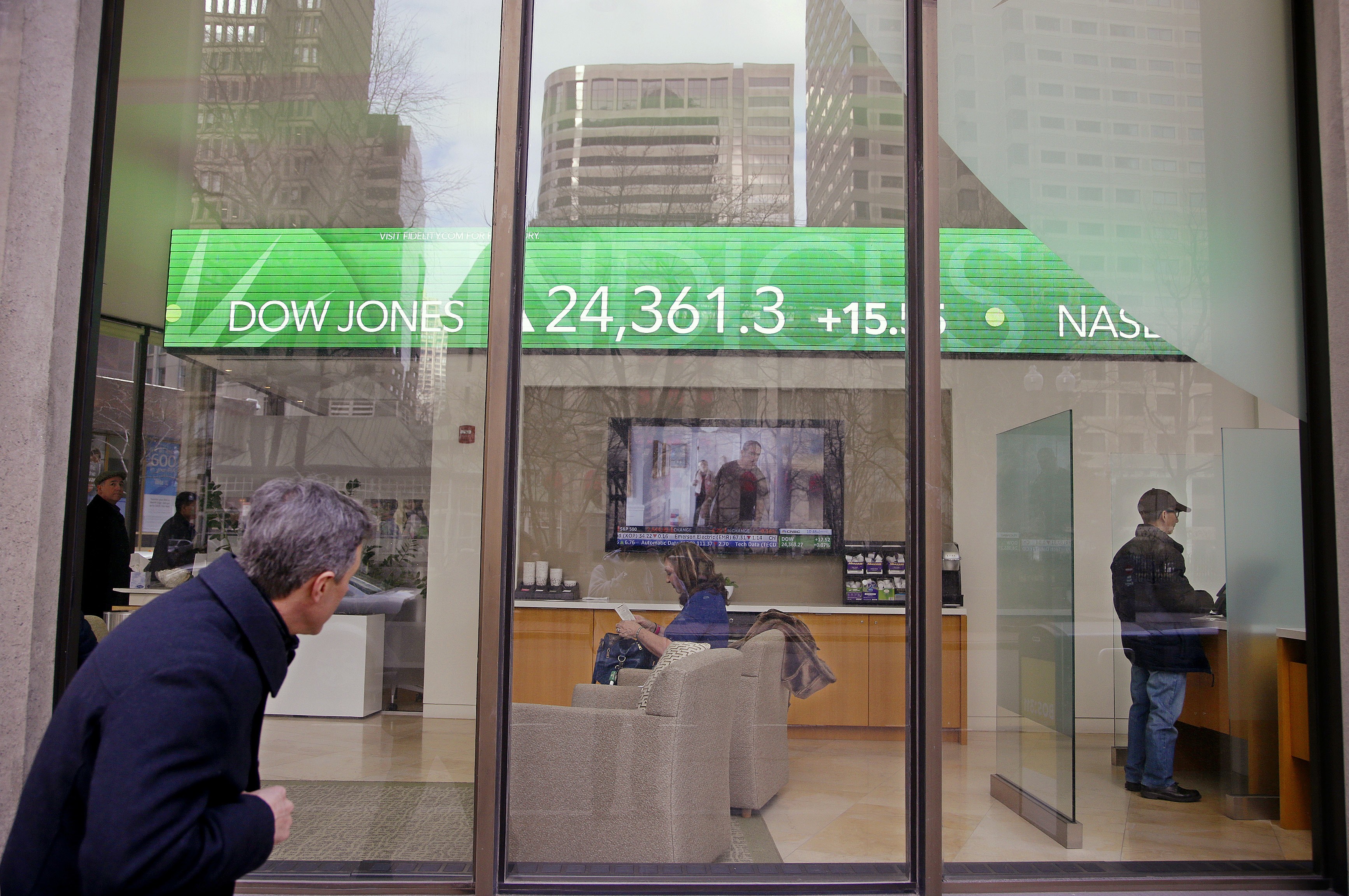 A passer-by peers in the window, while investors congregate inside at the Fidelity Investments office as the ticker displays stock market numbers. Over the last 10 years, passive indexing has crowded out active managers without any reversal in sight. Perhaps, suggests Peter Guy, recent market events and fund industry changes will revive active managers. Photo: AP