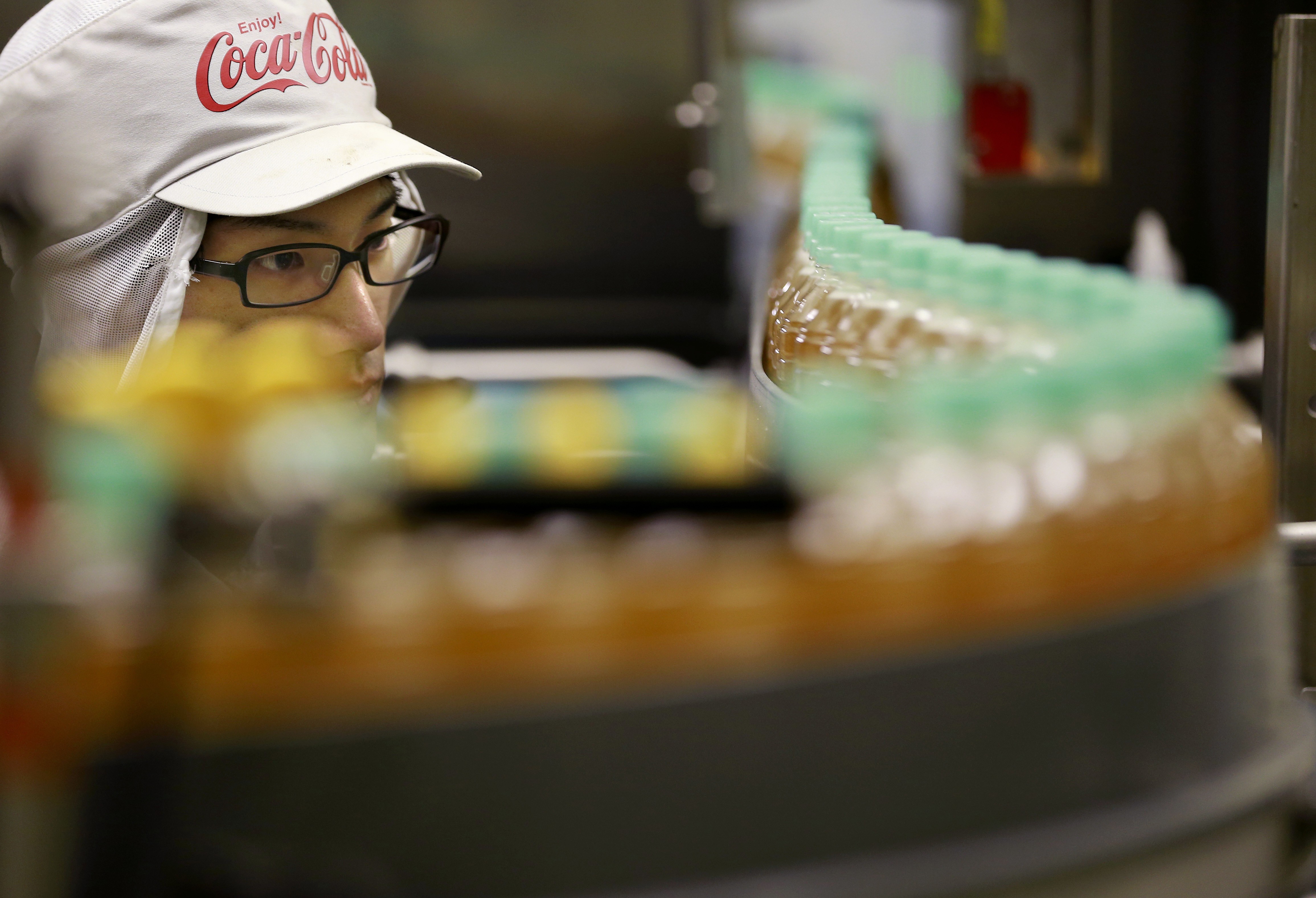 A worker watches a product line at Coca-Cola Ebina plant in Ebina, Kanagawa Prefecture, near Tokyo. The soda maker, best known for Coke, Sprite and Fanta, says it’s experimenting with a canned beverage that would be a mix of sparkling water and an alcoholic Japanese drink. Photo: AP