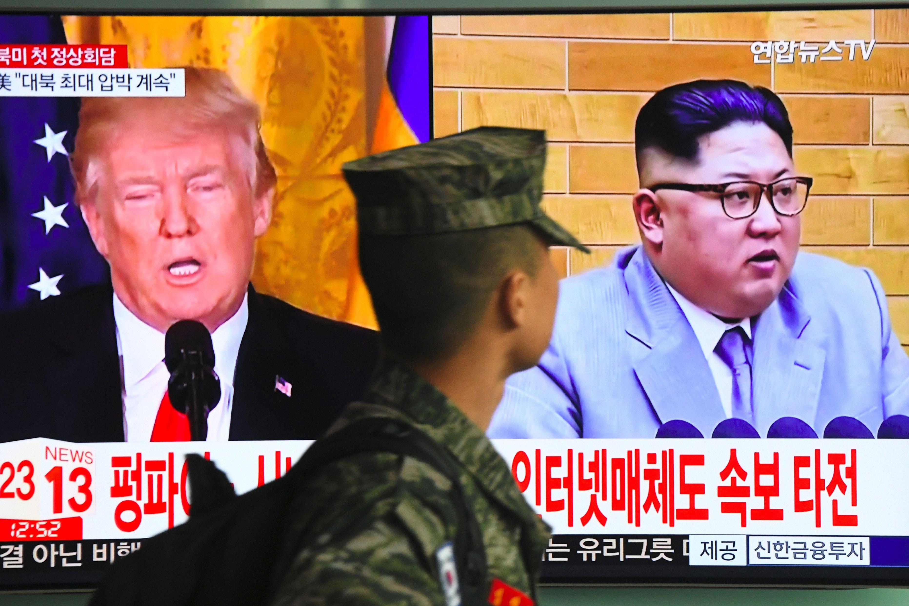 A South Korean soldier walks past a television screen showing pictures of US President Donald Trump (left) and North Korean leader Kim Jong-un at a railway station in Seoul on March 9. Trump agreed on March 8 to a historic first meeting with Kim. Photo: AFP