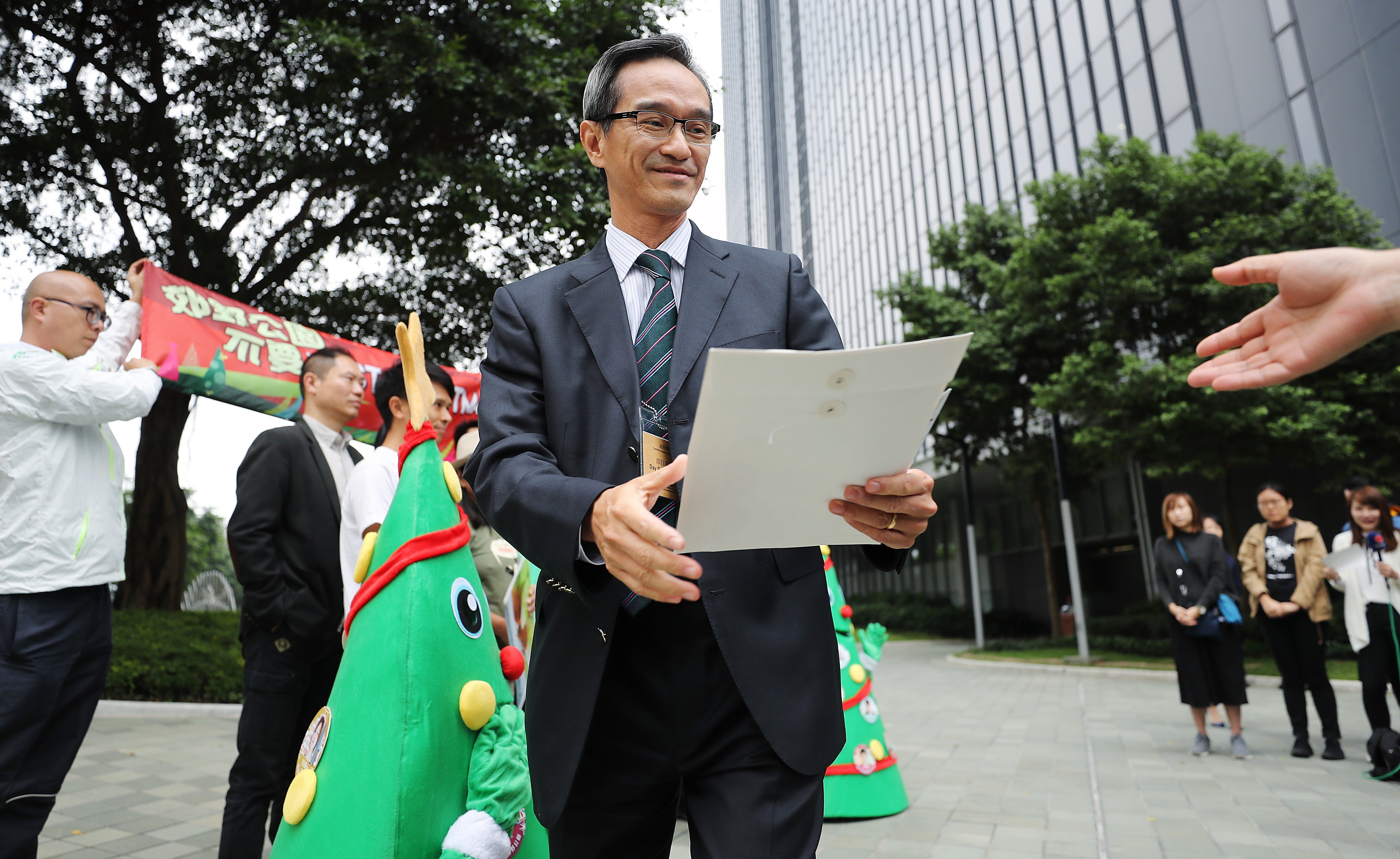 The chairman of the Task Force on Land Supply, Stanley Wong Yuen-fai, receives petition letters from Greenpeace campaigners urging the task force to safeguard country parks, outside the Hong Kong government headquarters, in Admiralty last December 5. Photo: Winson Wong