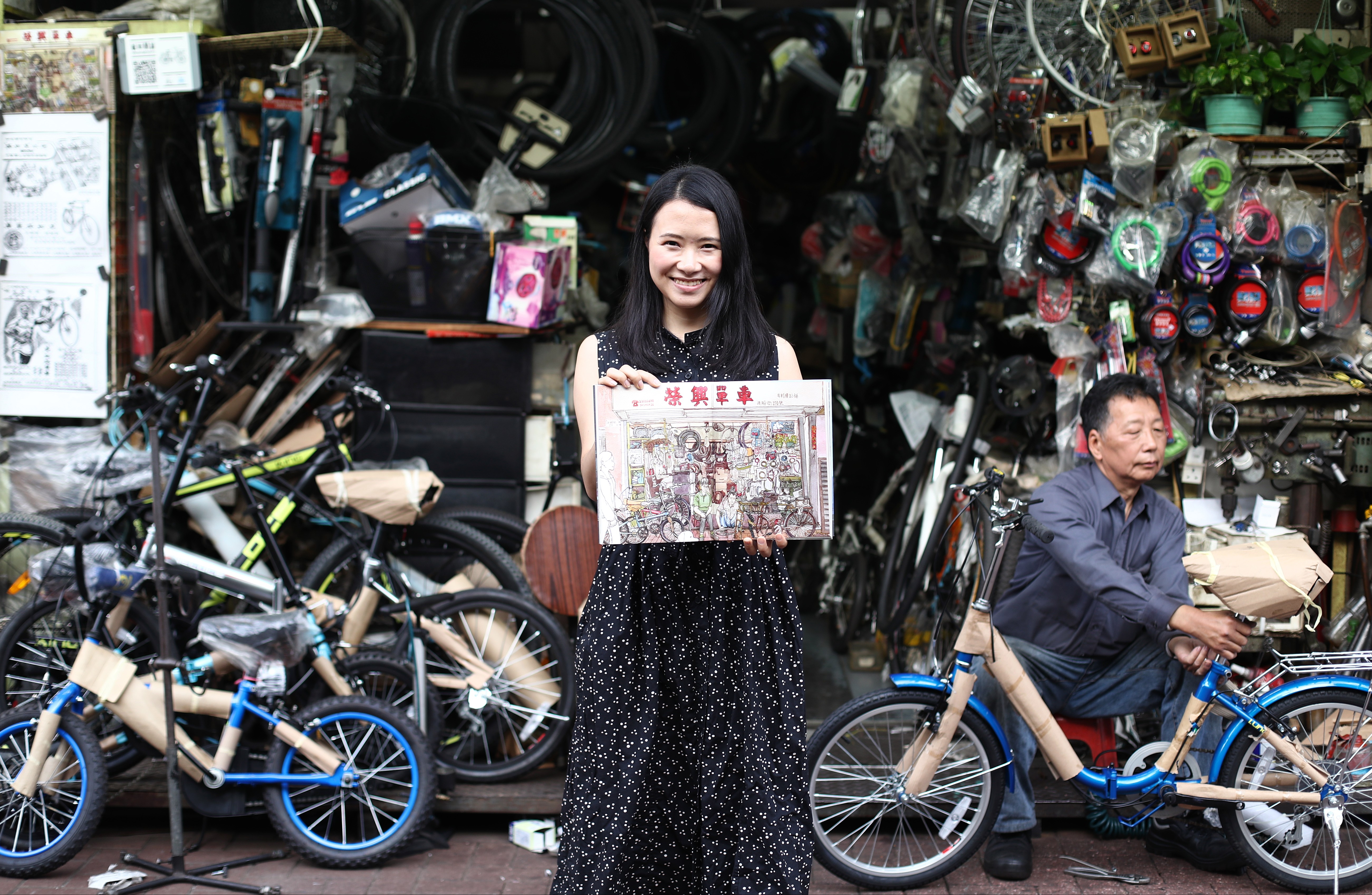 Illustrator Or Wai-wai displays a drawing of Wing Hing Bicycle outside the shop in Yau Ma Tei. Photo: Nora Tam
