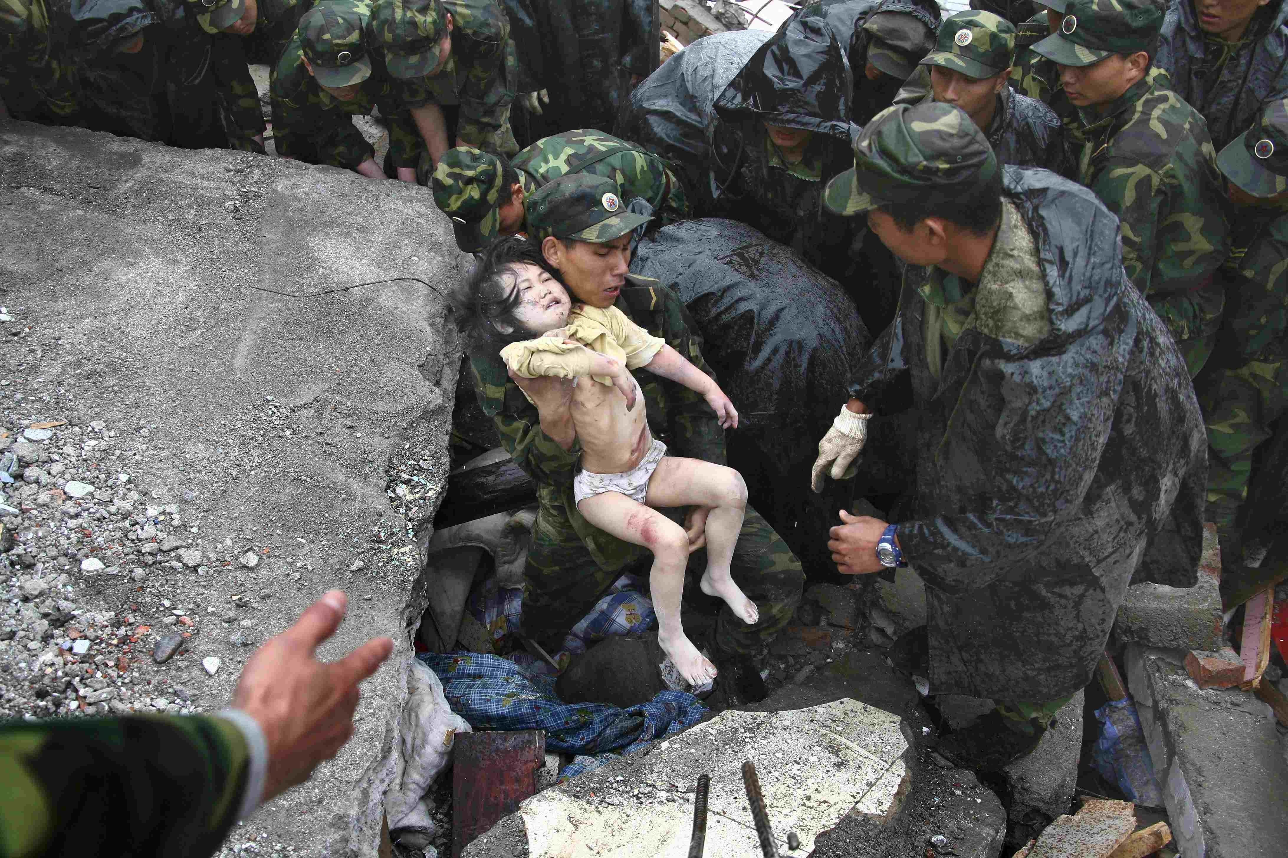 Soldiers rescue a child from the rubble after the magnitude-8 earthquake in Beichuan, Sichuan province May 13, 2008. Photo: Reuters