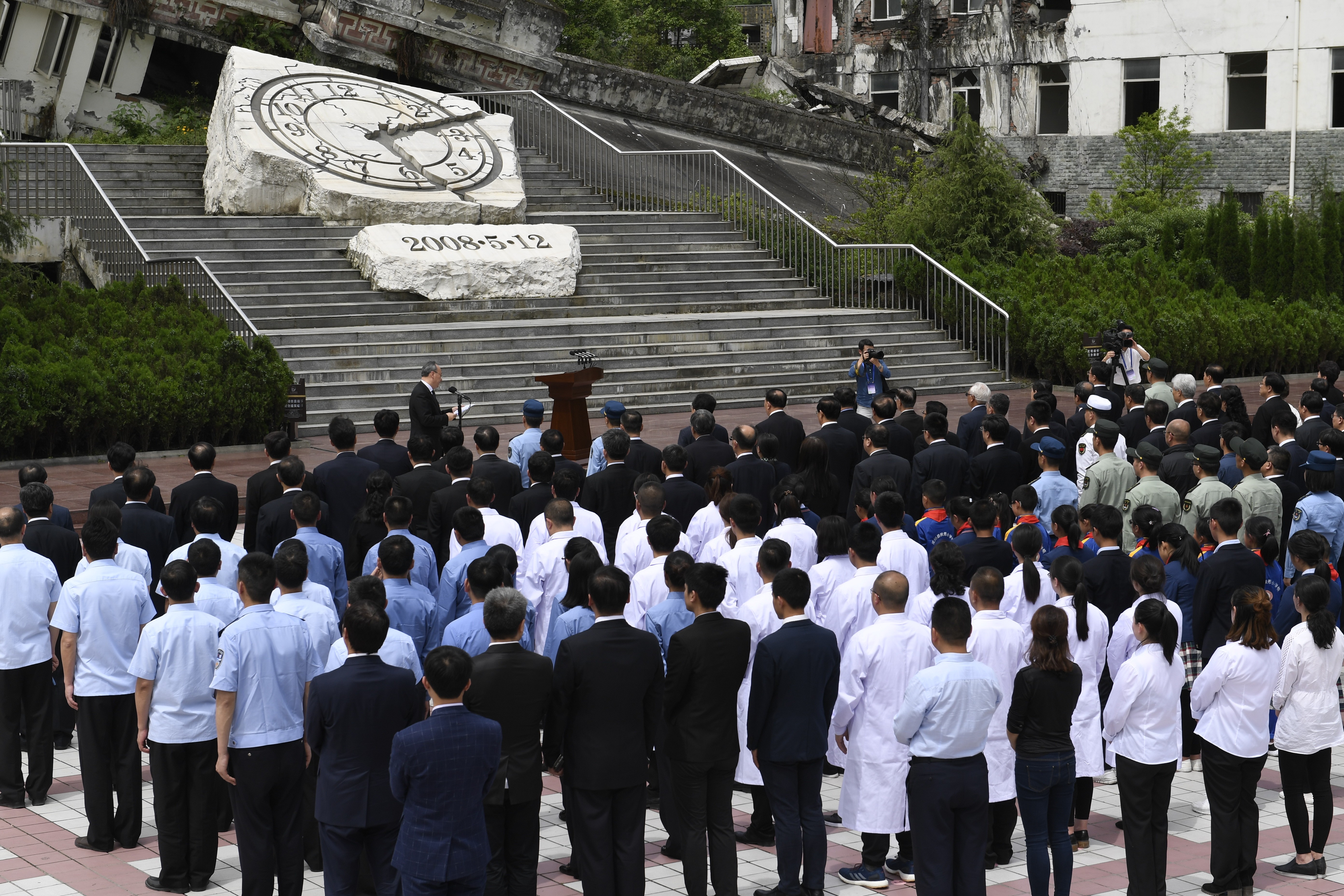 An official ceremony is held outside the Xuankou Middle School, which is now a memorial site where the hands of a broken clock are frozen at 2.28pm – the time the earthquake struck. Photo: Xinhua