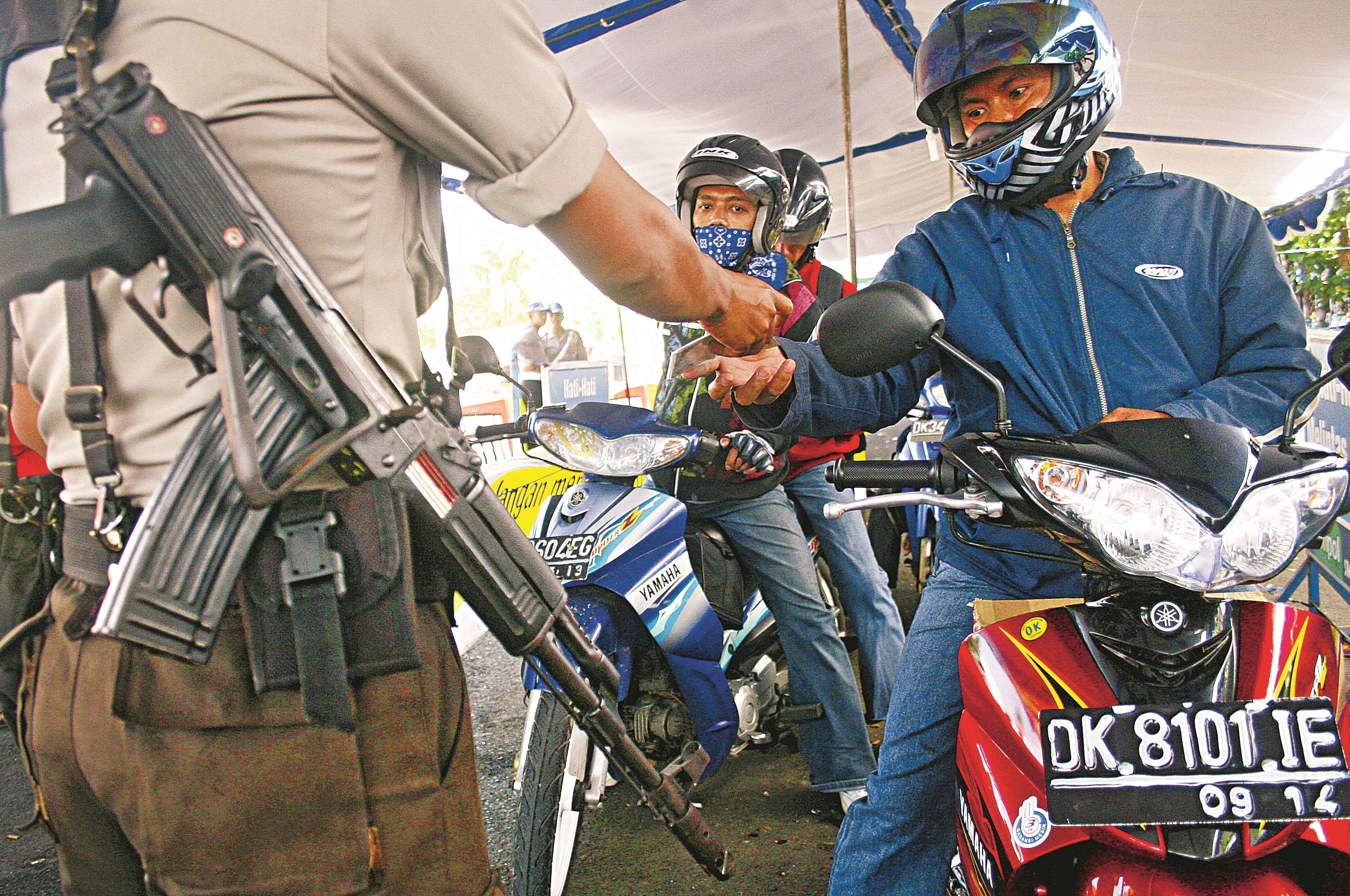 An armed policeman holds a security check to motorists at Bali’s Gilimanuk ferry port. Photo: AFP