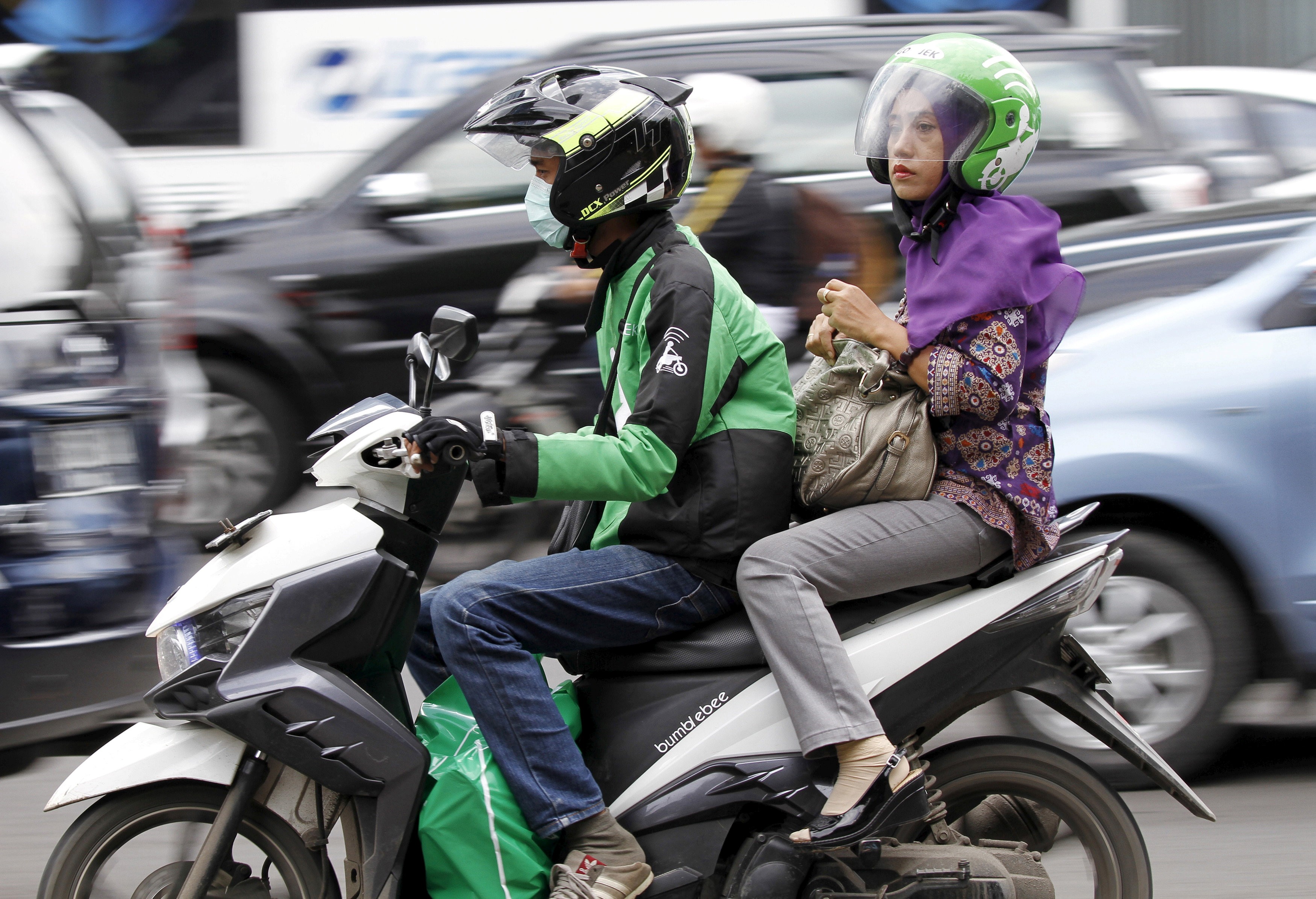 A woman rides on the back of a motorbike from ride-hailing firm Go-Jek in Jakarta in December 2015. Firms providing innovative services might shift Asian economies’ reliance on manufacturing to stimulate growth. Photo: Reuters