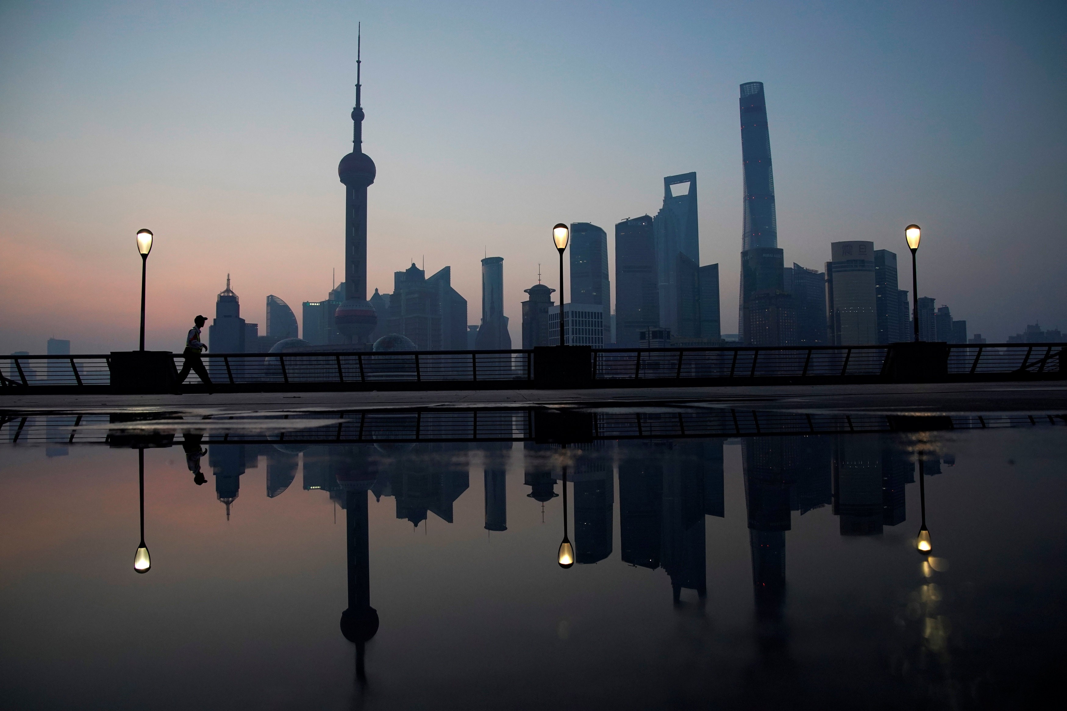 A security guard walks on the bund in front of the financial district of Pudong in Shanghai. Photo: Reuters
