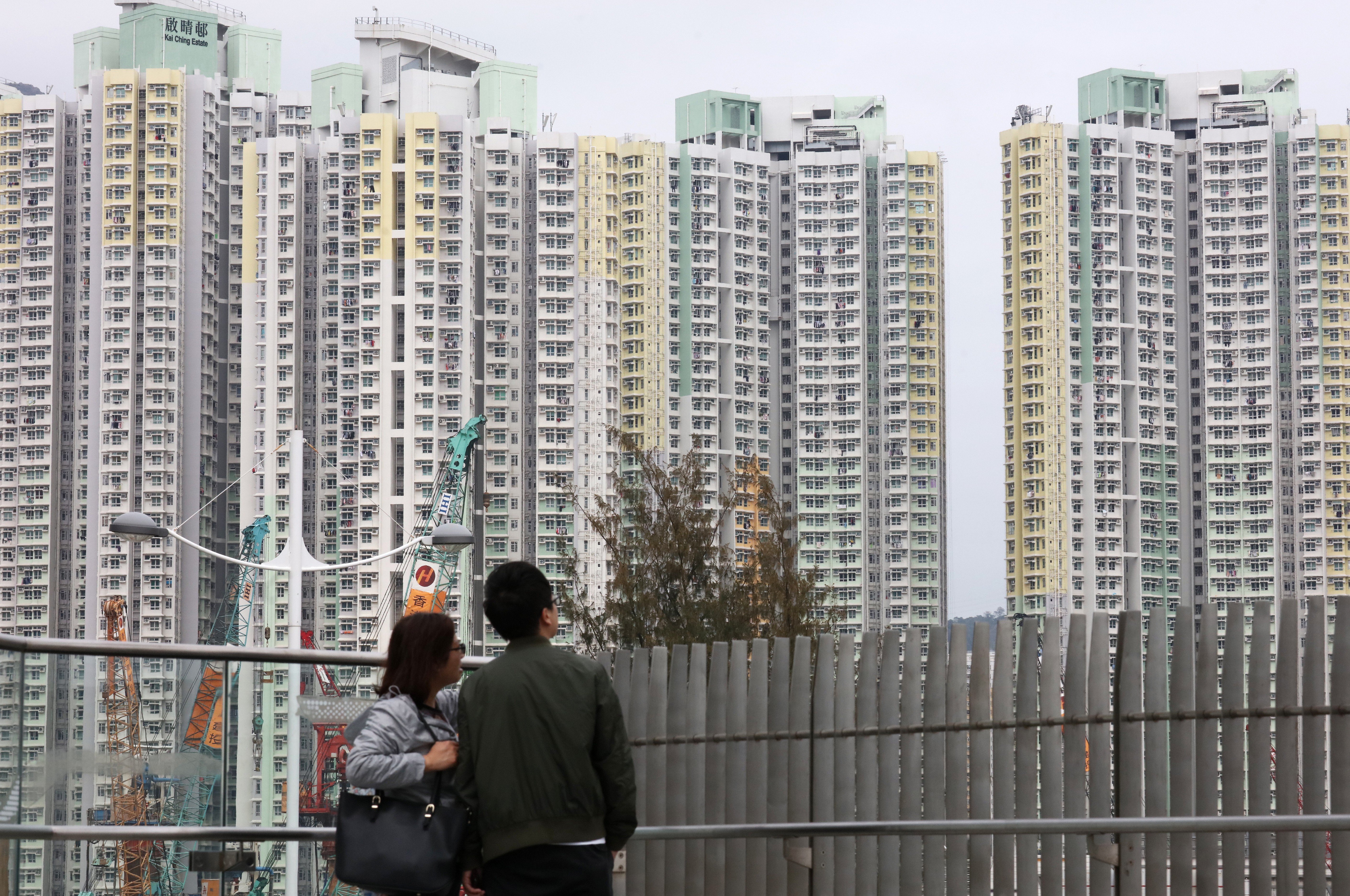 A man and a woman look out on residential buildings at Kai Ching Estate in Kai Tak. Hong Kong’s “housing ladder” allowing young adults to start with public housing and work towards homeownership has broken, thanks to out-of-control rent increases and especially high down-payment requirements. Photo: Felix Wong