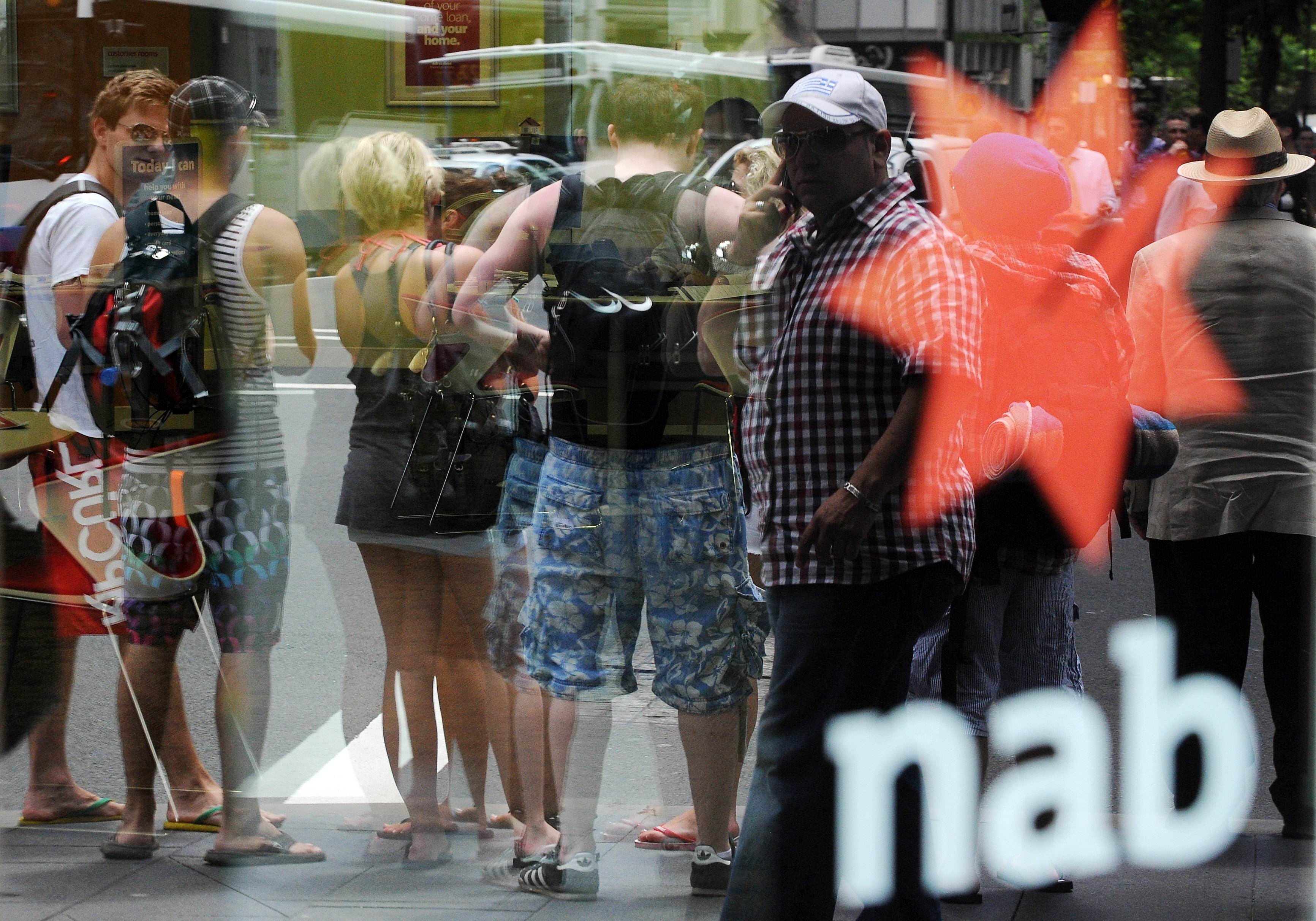 Passers-by are reflected in the glass door of a National Australia Bank branch in Sydney in October 2010. A royal commission is looking into allegations that Australian banks have engaged in several malpractices, such as bribery, forged documents and denial of responsible lending obligations. Photo: AFP