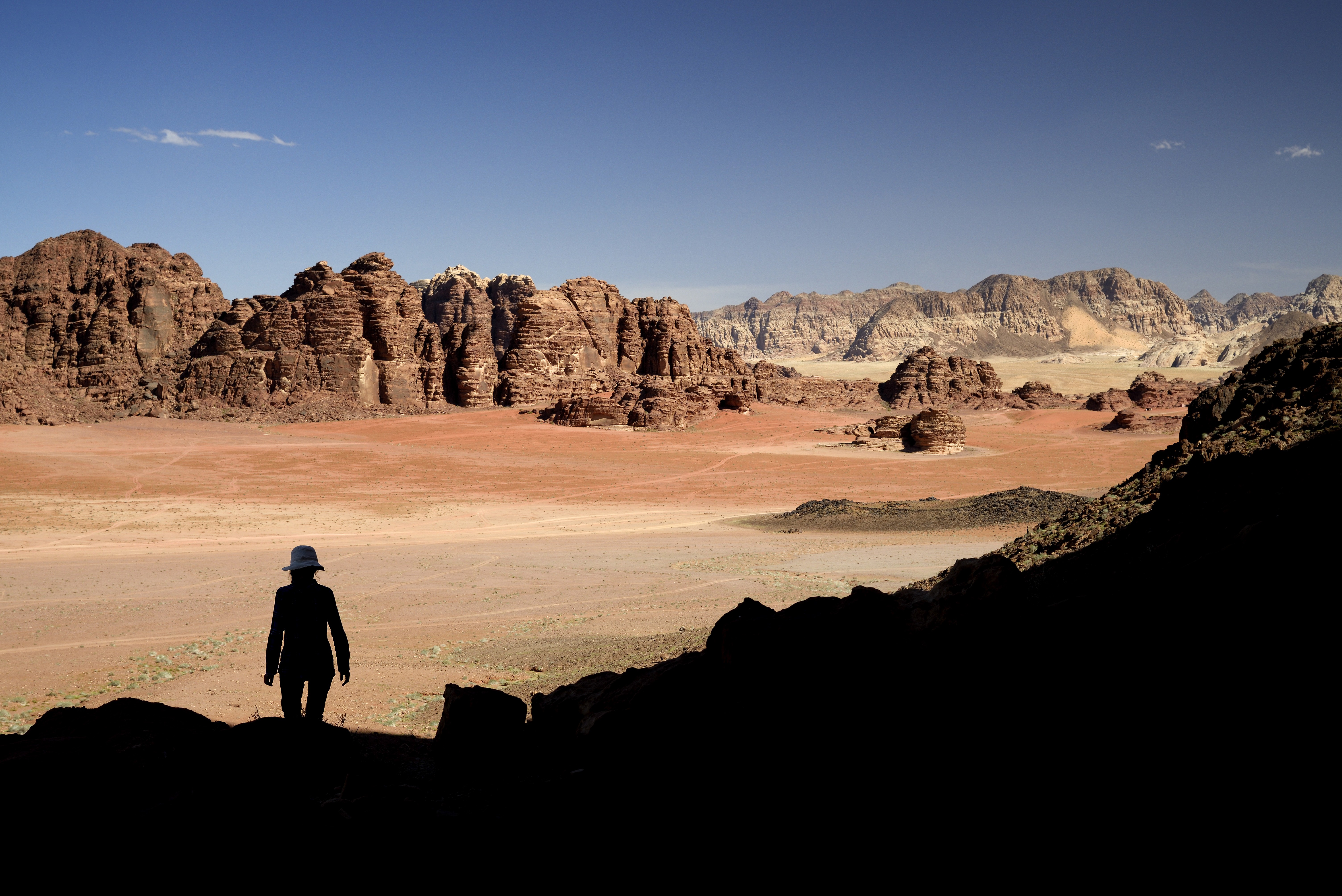 Steep cliffs tower over the red sand desert of Wadi Rum, a sandstone valley in southern Jordan. Photo: Photononstop