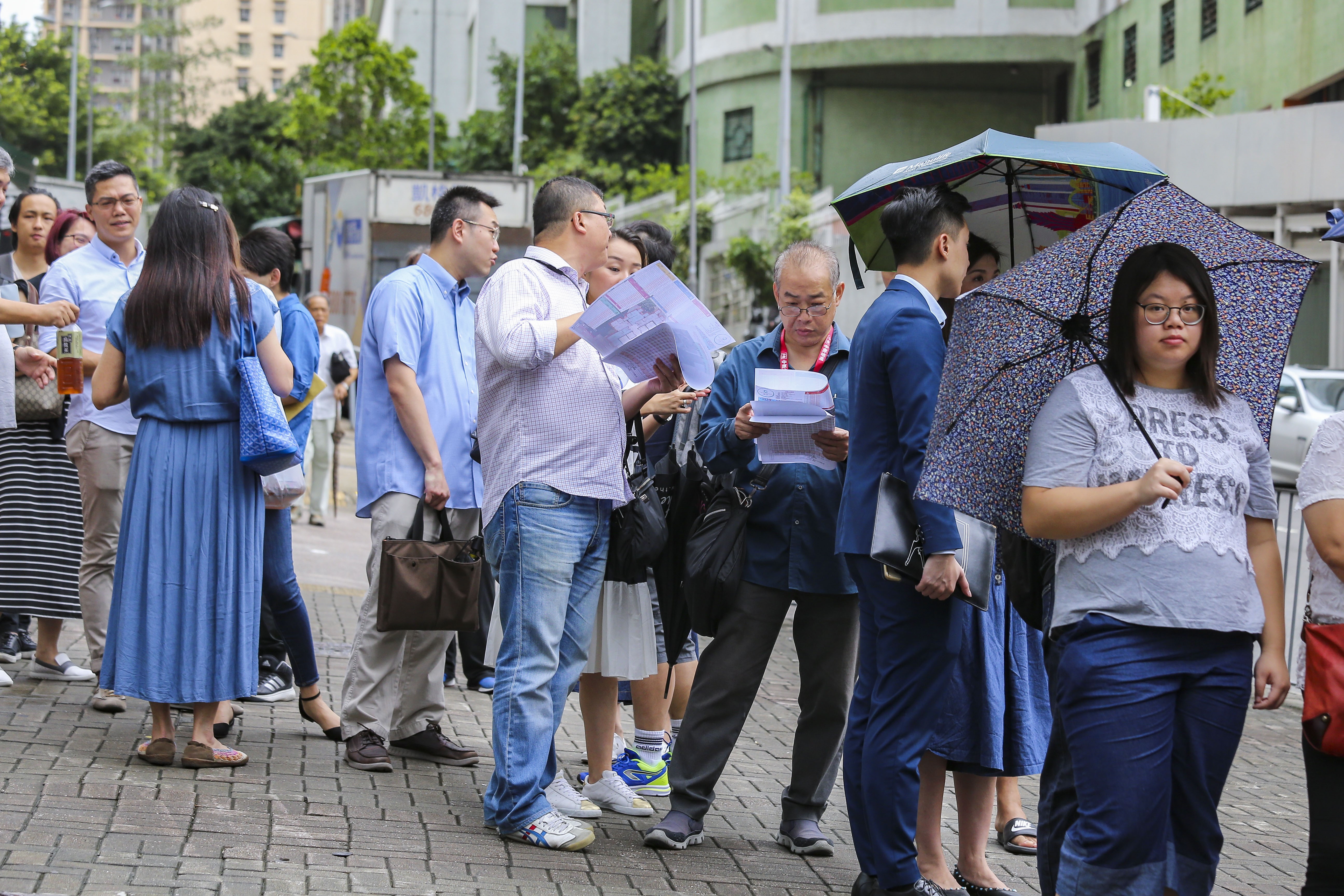 Potential buyers faced heavy downpours and gusty winds as they queued up for the two property sales. Photo: Dickson Lee