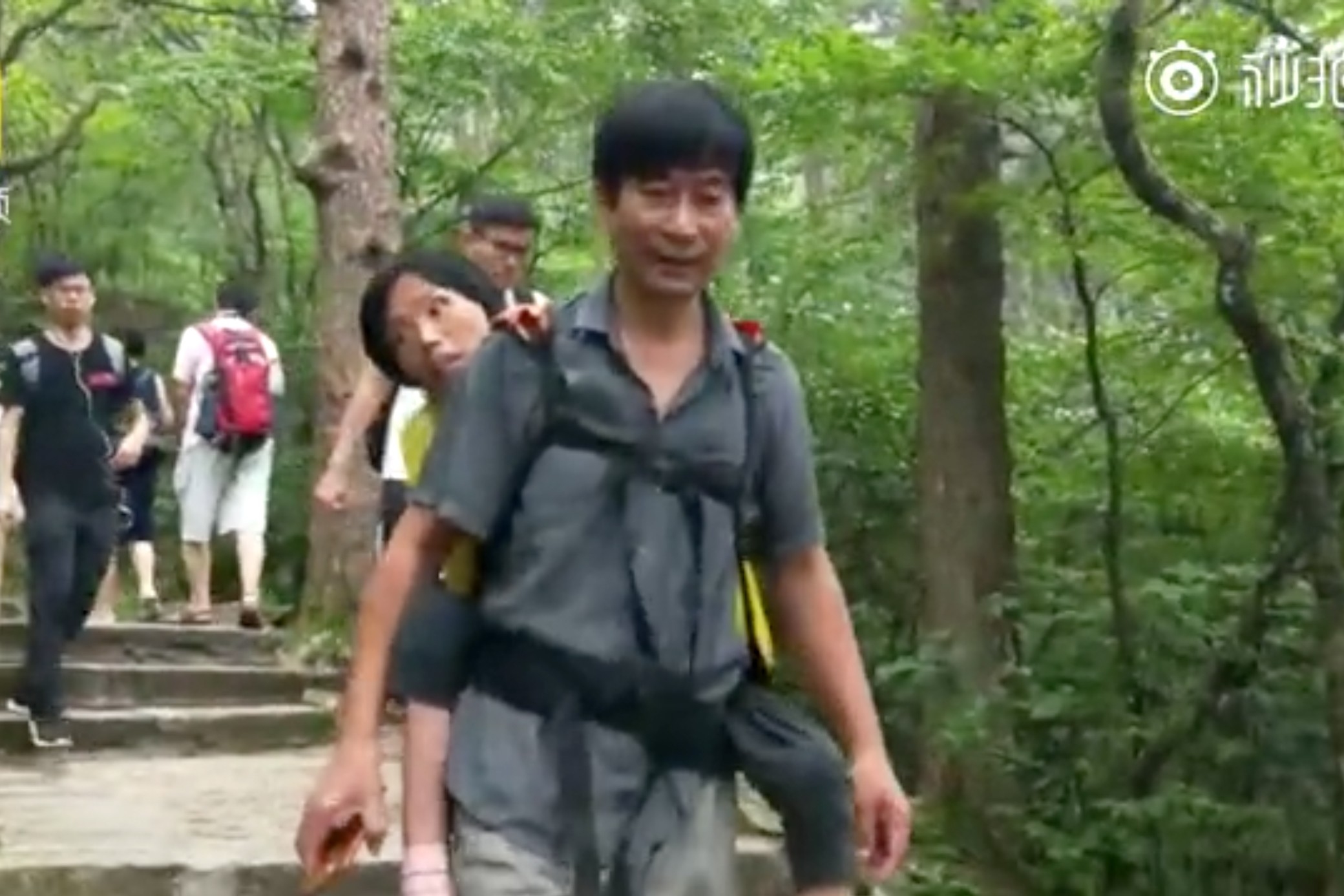 A husband carried his wife, who suffers from motor neurone disease, on his back up one of China’s most famous mountains. Photo: Pear Video