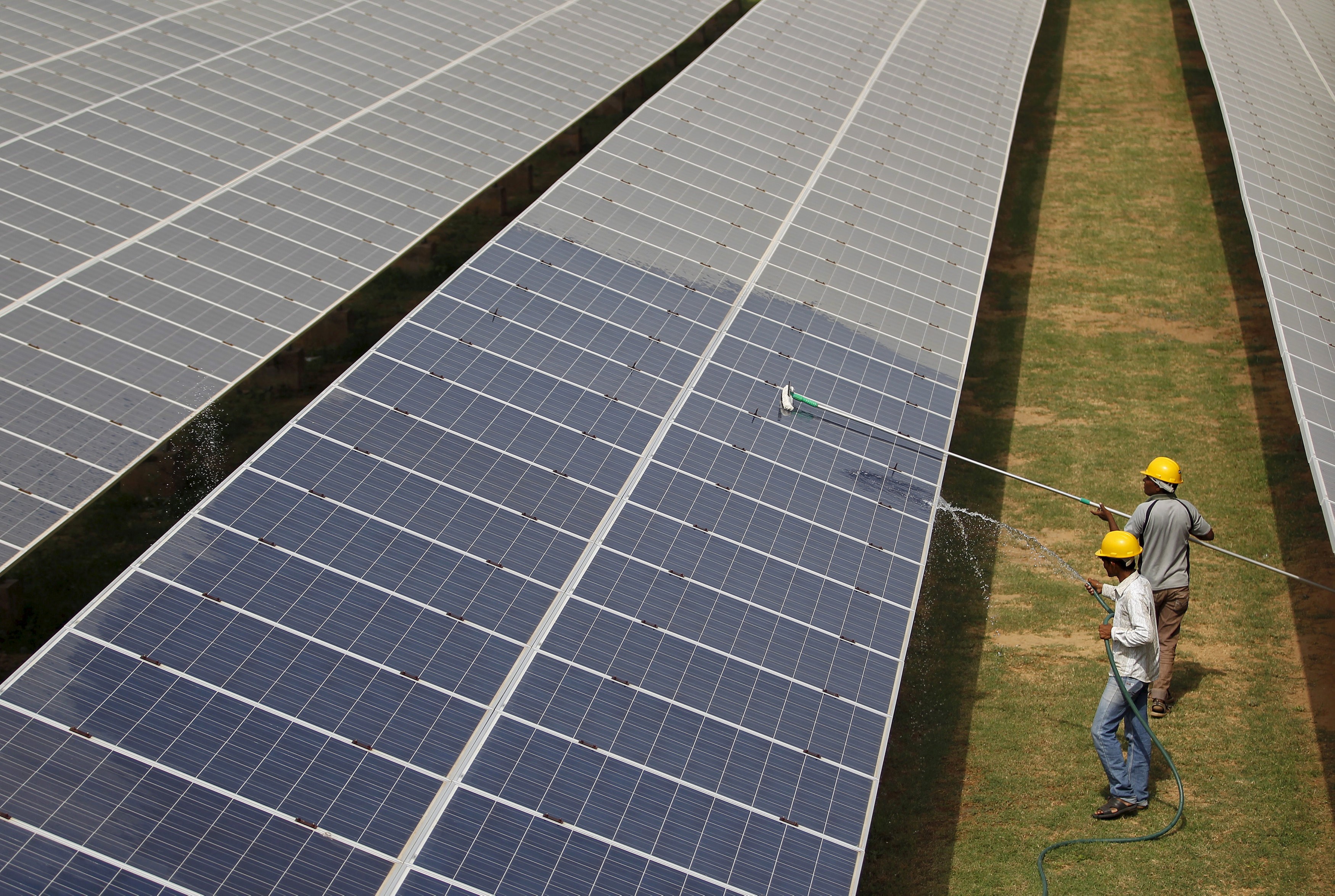 Workers clean a solar power plant in Gujarat, India. Photo: Reuters