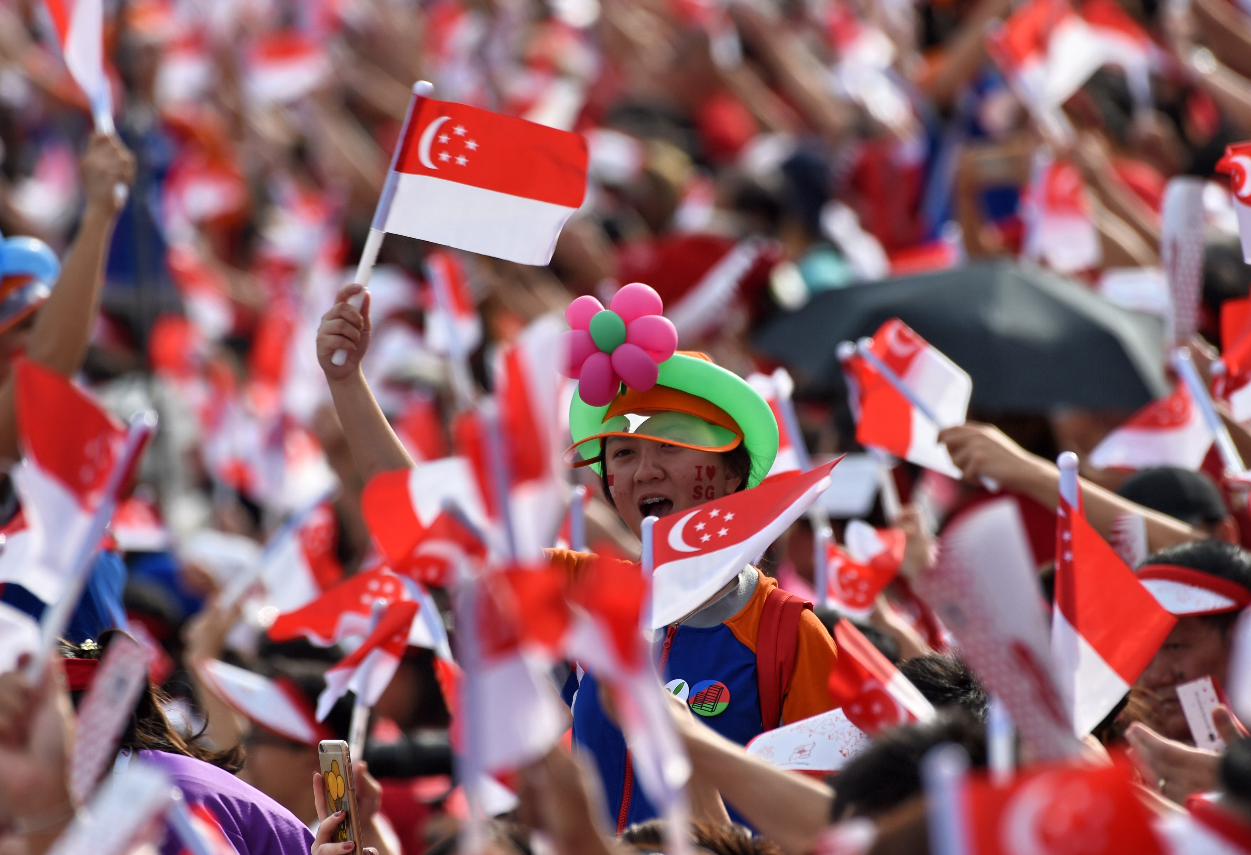 Spectators wave Singaporean flags during their country’s 52nd National Day parade and celebration in Singapore last year. Photo: AFP