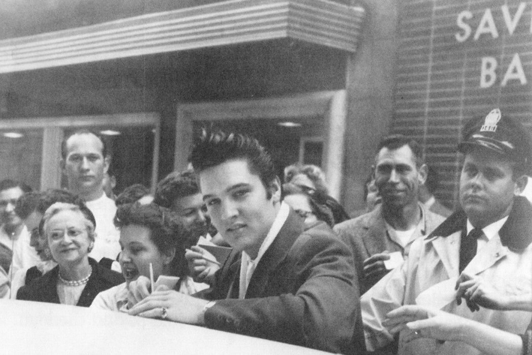 A young Elvis Presley – who died 41 years ago on August 16 – signs autographs for a crowd of fans after being spotted while out in Memphis, the United States, on December 11, 1956.