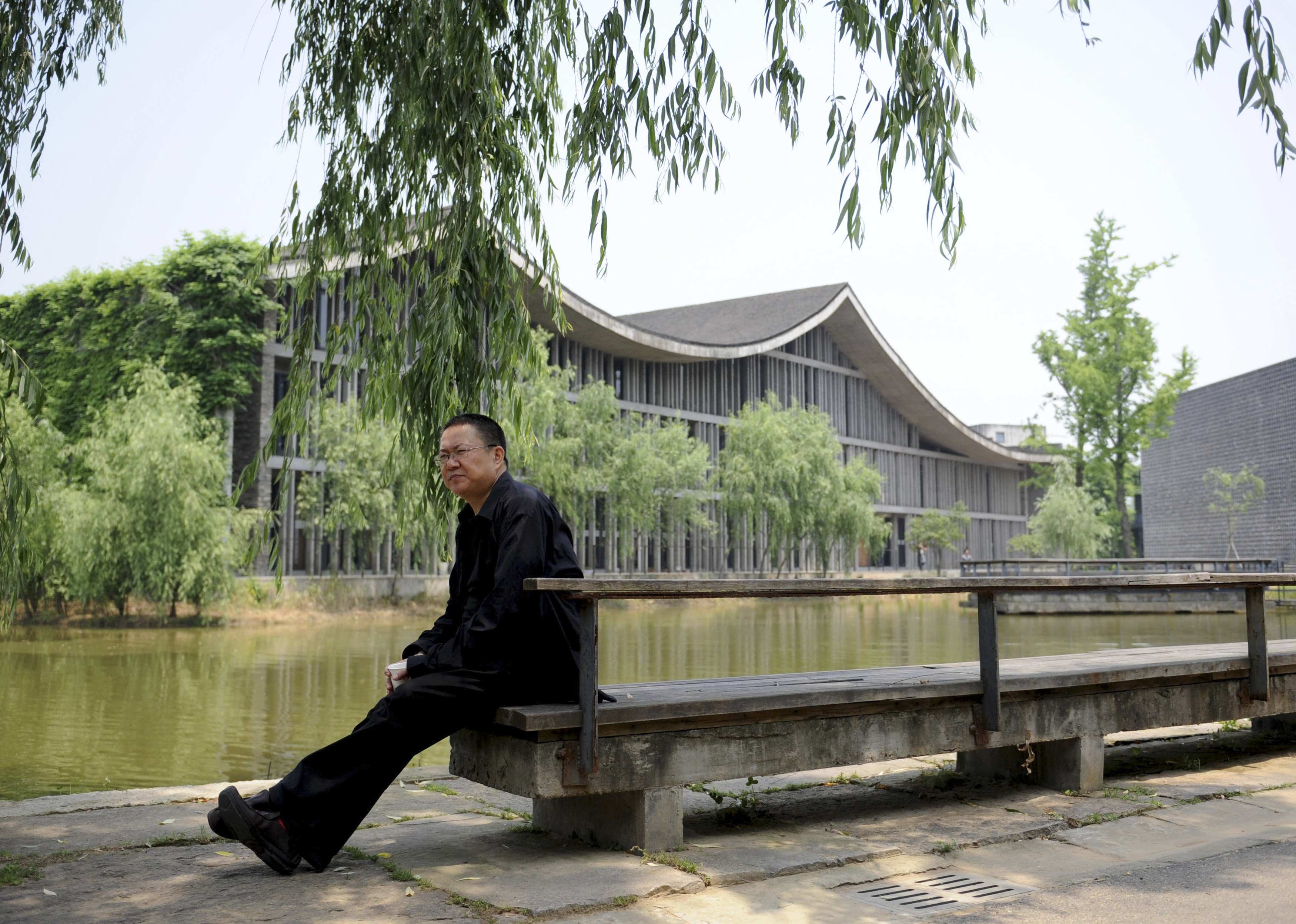 Pritzker Prize-winning architect Wang Shu sitting on a bench at the Xiangshan Campus, which he and his wife designed, at the China Academy of Art in Hangzhou. Photo: Reuters