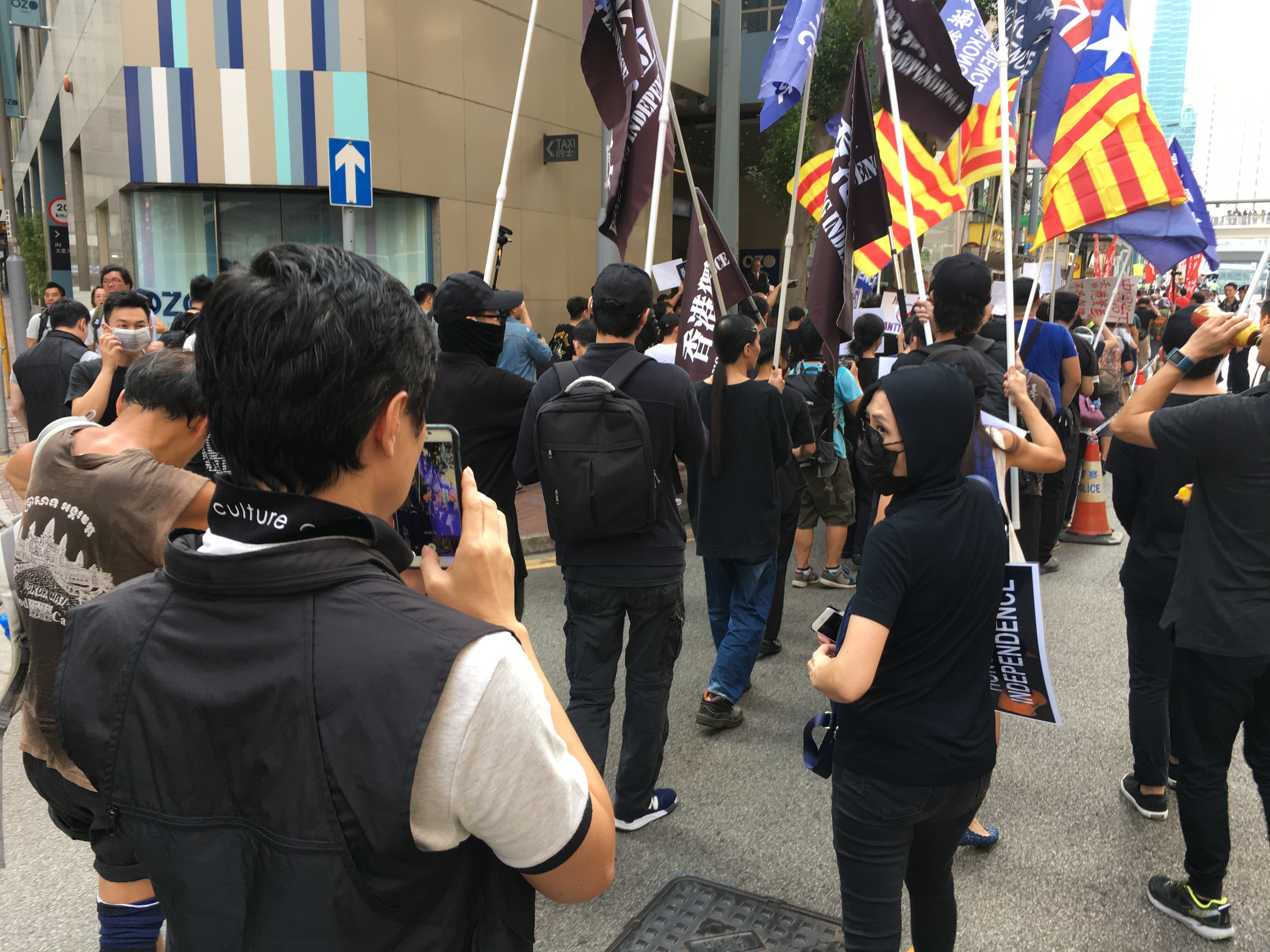 Police officers film pro-independence marchers carrying the Catalan flag. Photo: Alvin Lum
